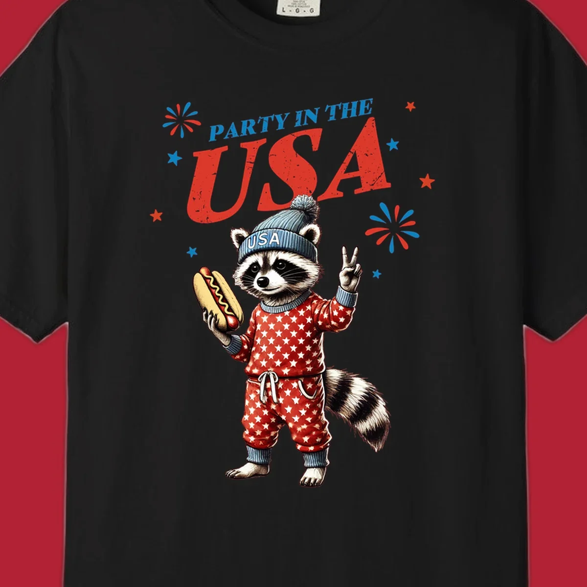 A cartoon raccoon wearing a USA beanie and star-patterned pajamas, holding a hotdog and making a peace sign, with 'PARTY IN THE USA' text and fireworks.