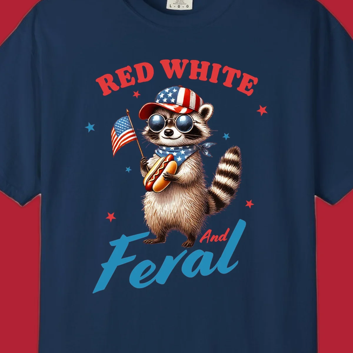 A cartoon raccoon wearing a patriotic hat and bandana, holding an American flag and a hot dog, with 'Red White And Feral' text. This is a red-white-feral-raccoon design.