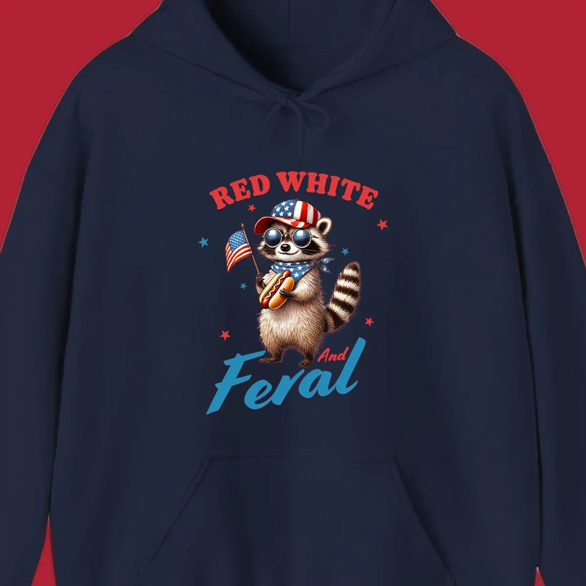 A cartoon raccoon wearing a patriotic hat and bandana, holding an American flag and a hot dog, with 'Red White And Feral' text. This is a red-white-feral-raccoon design.