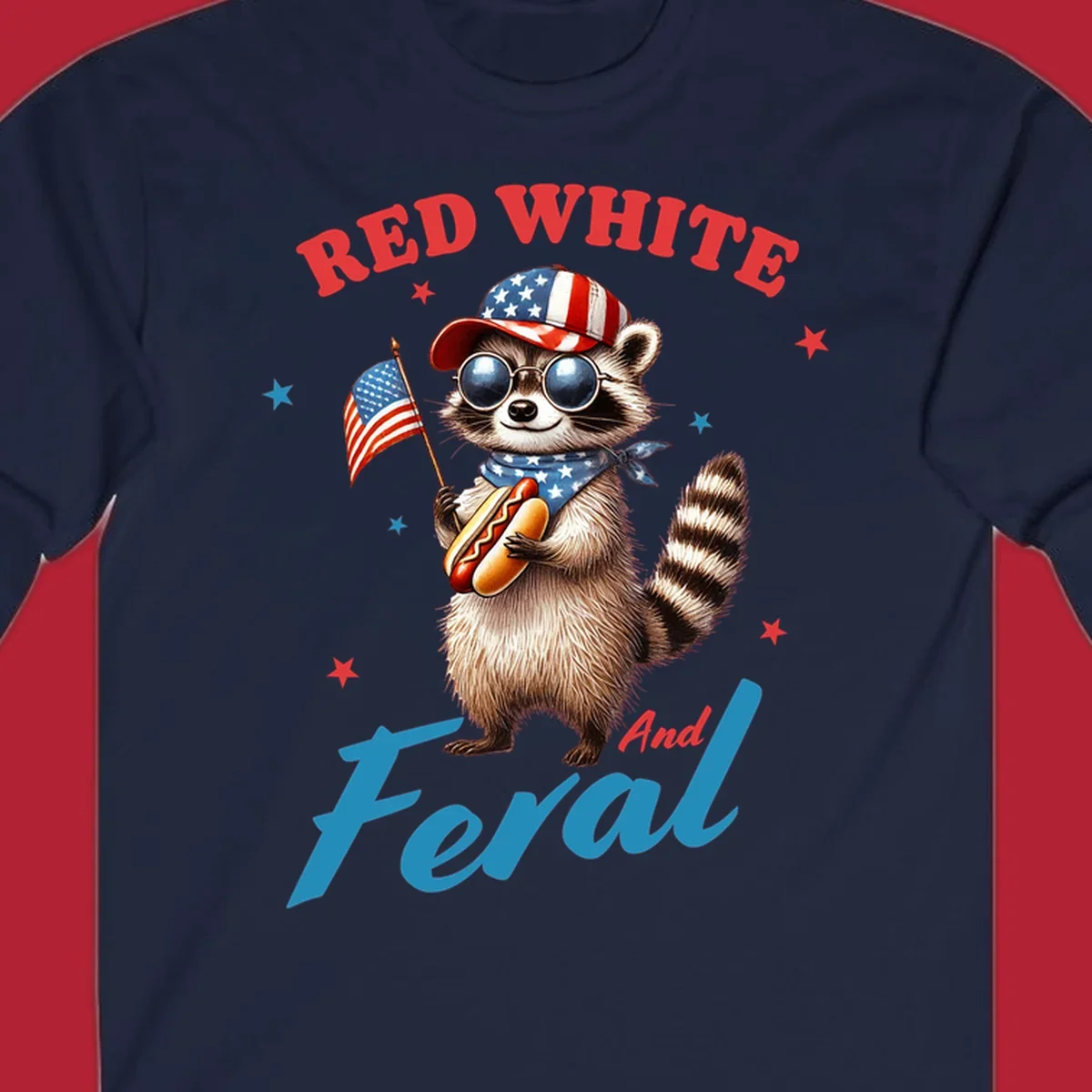 A cartoon raccoon wearing a patriotic hat and bandana, holding an American flag and a hot dog, with 'Red White And Feral' text. This is a red-white-feral-raccoon design.