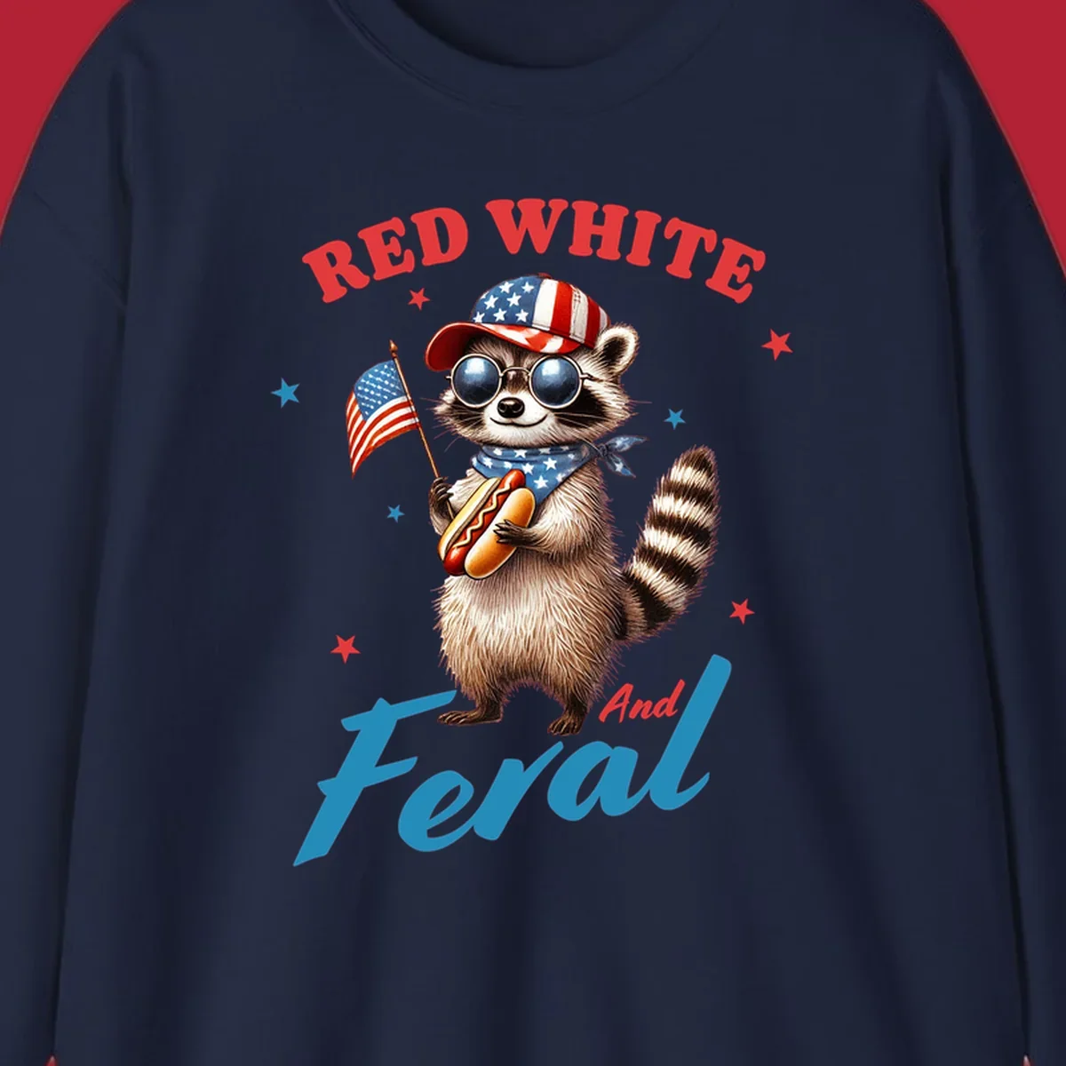 A cartoon raccoon wearing a patriotic hat and bandana, holding an American flag and a hot dog, with 'Red White And Feral' text. This is a red-white-feral-raccoon design.
