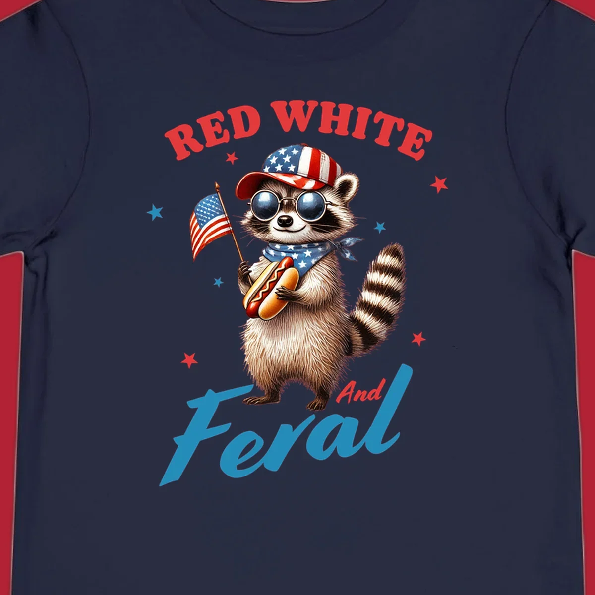 A cartoon raccoon wearing a patriotic hat and bandana, holding an American flag and a hot dog, with 'Red White And Feral' text. This is a red-white-feral-raccoon design.