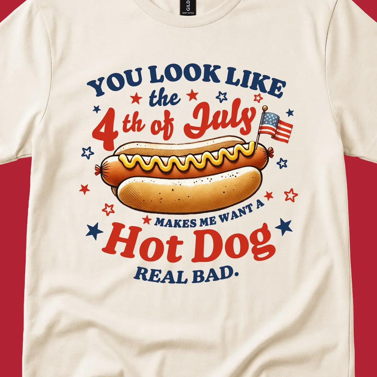 An illustrated hot dog with mustard, American flags, and stars. Text reads "YOU LOOK LIKE the 4th of July MAKES ME WANT A Hot Dog REAL BAD." you-look-like-4th-july design.