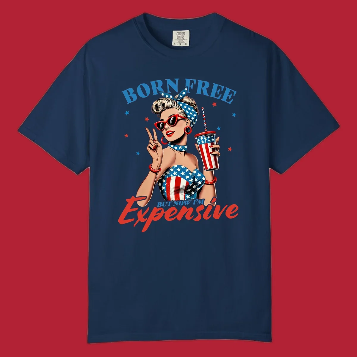 A vintage pin-up girl with a patriotic outfit and cup, making a peace sign, with the text "Born Free But Now I'm Expensive". This born-free-expensive-pinup design is surrounded by stars.