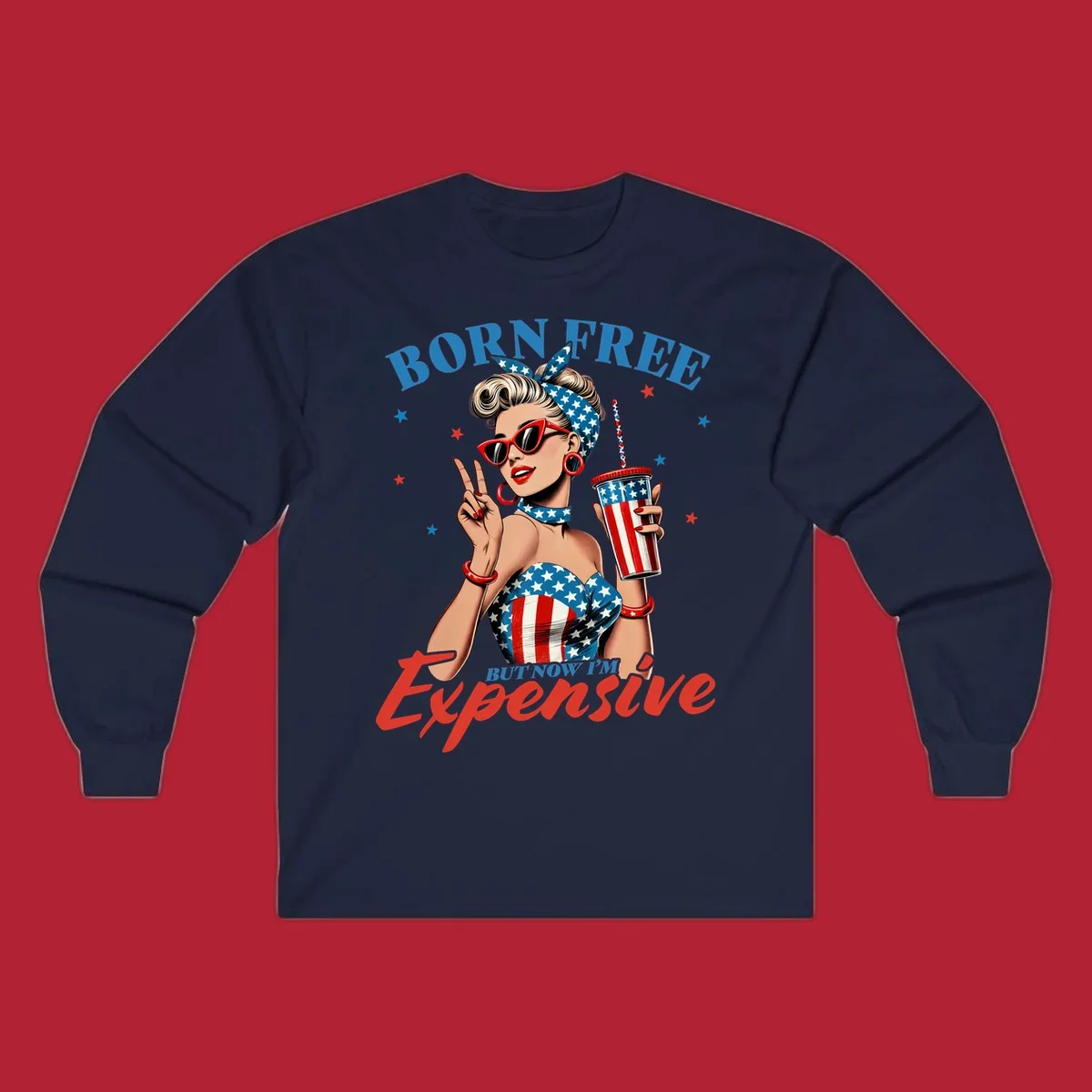 A vintage pin-up girl with a patriotic outfit and cup, making a peace sign, with the text "Born Free But Now I'm Expensive". This born-free-expensive-pinup design is surrounded by stars.