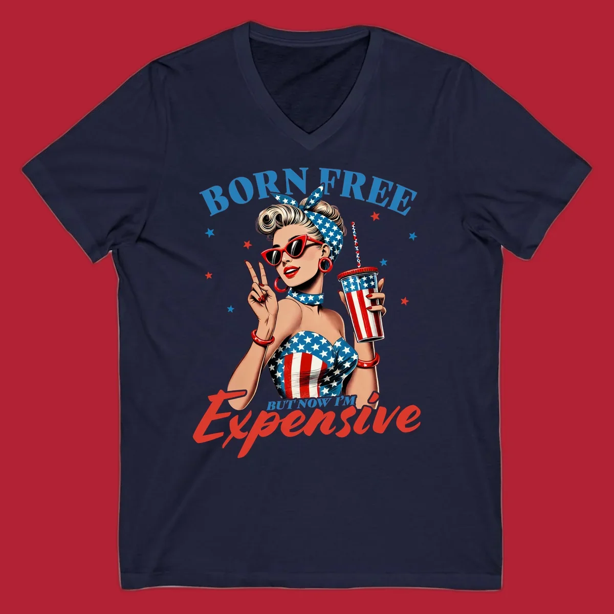 A vintage pin-up girl with a patriotic outfit and cup, making a peace sign, with the text "Born Free But Now I'm Expensive". This born-free-expensive-pinup design is surrounded by stars.