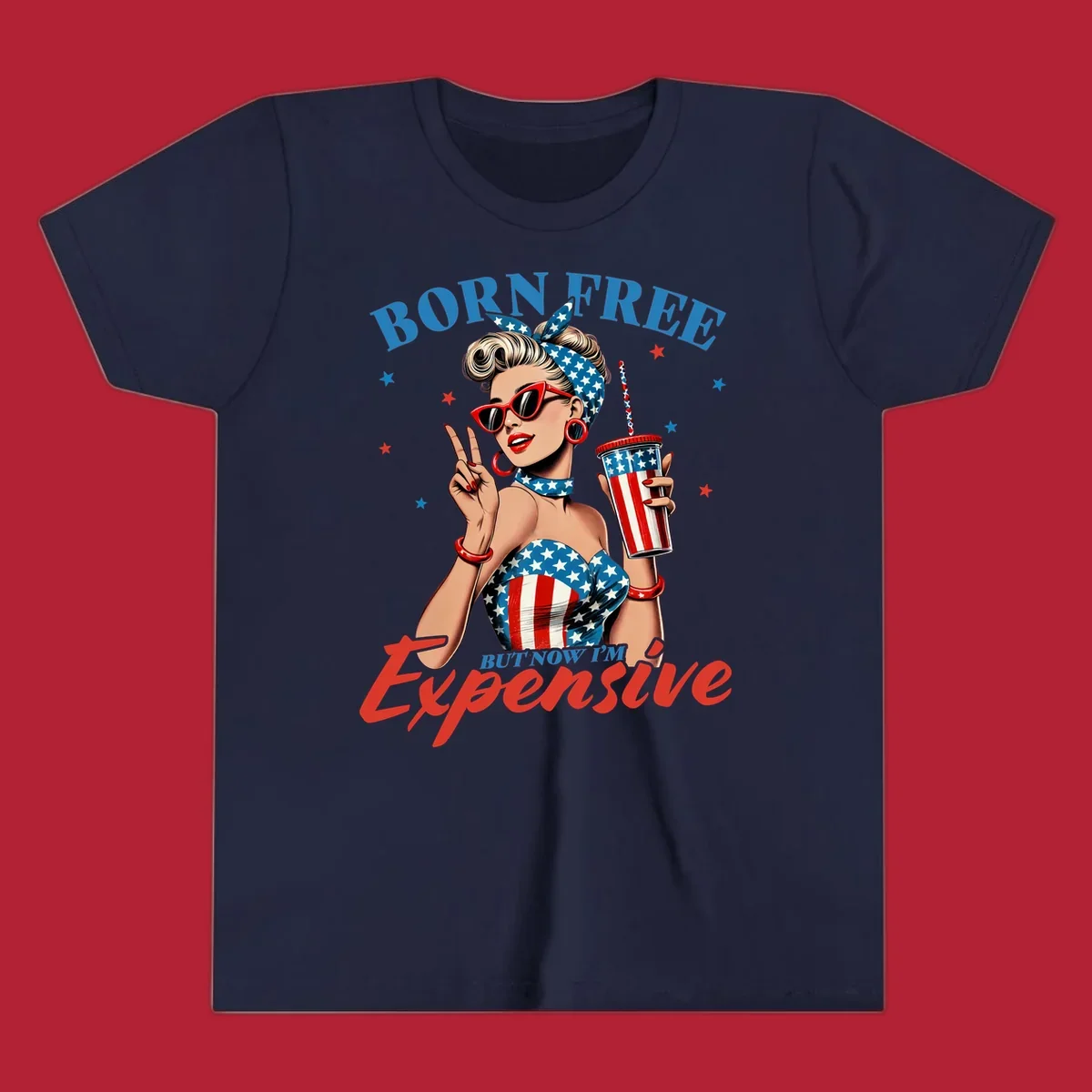 A vintage pin-up girl with a patriotic outfit and cup, making a peace sign, with the text "Born Free But Now I'm Expensive". This born-free-expensive-pinup design is surrounded by stars.