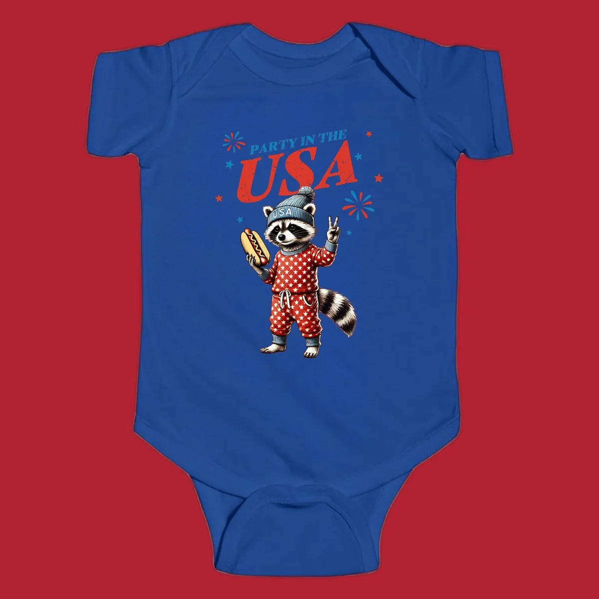 A cartoon raccoon wearing a USA beanie and star-patterned pajamas, holding a hotdog and making a peace sign, with 'PARTY IN THE USA' text and fireworks.
