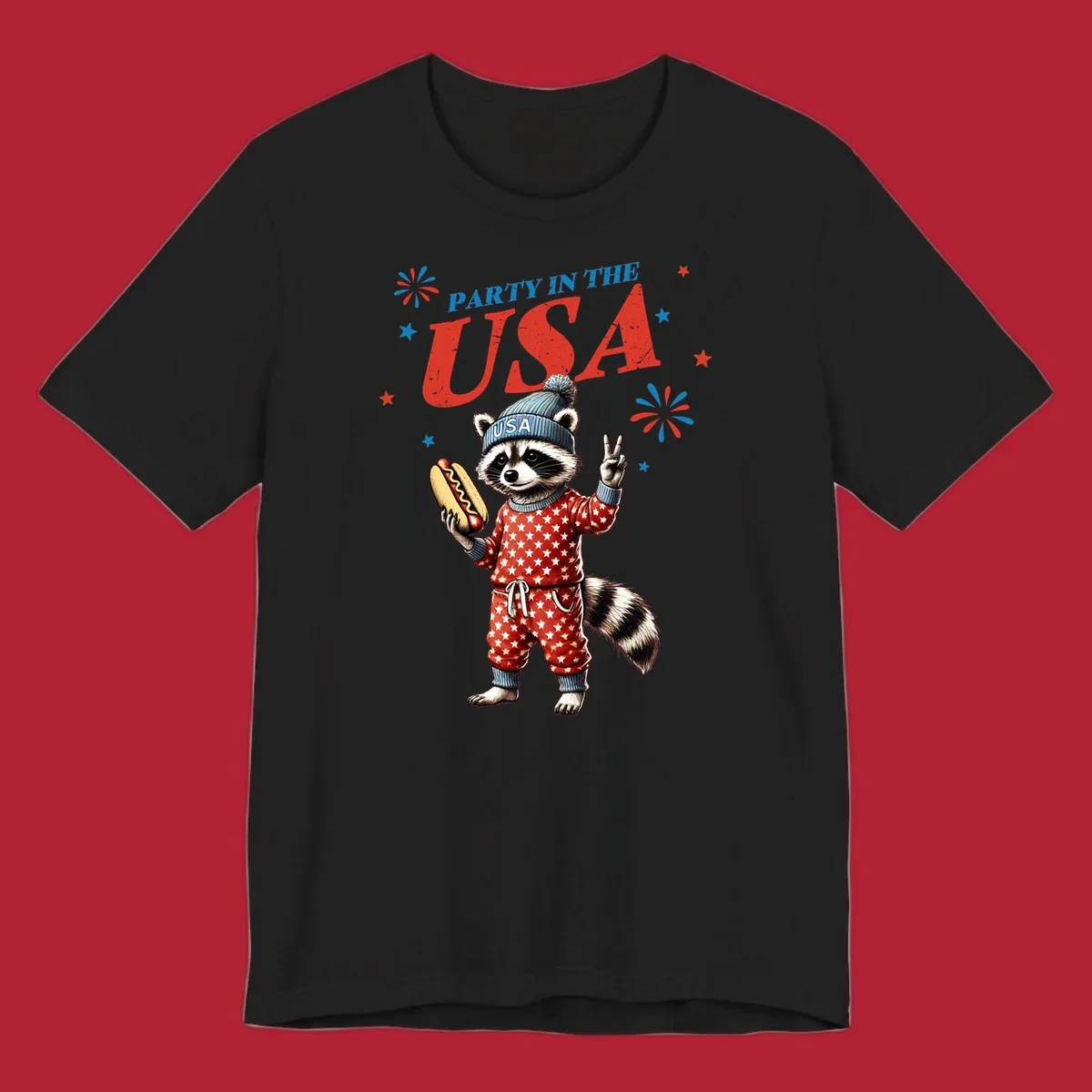 A cartoon raccoon wearing a USA beanie and star-patterned pajamas, holding a hotdog and making a peace sign, with 'PARTY IN THE USA' text and fireworks.