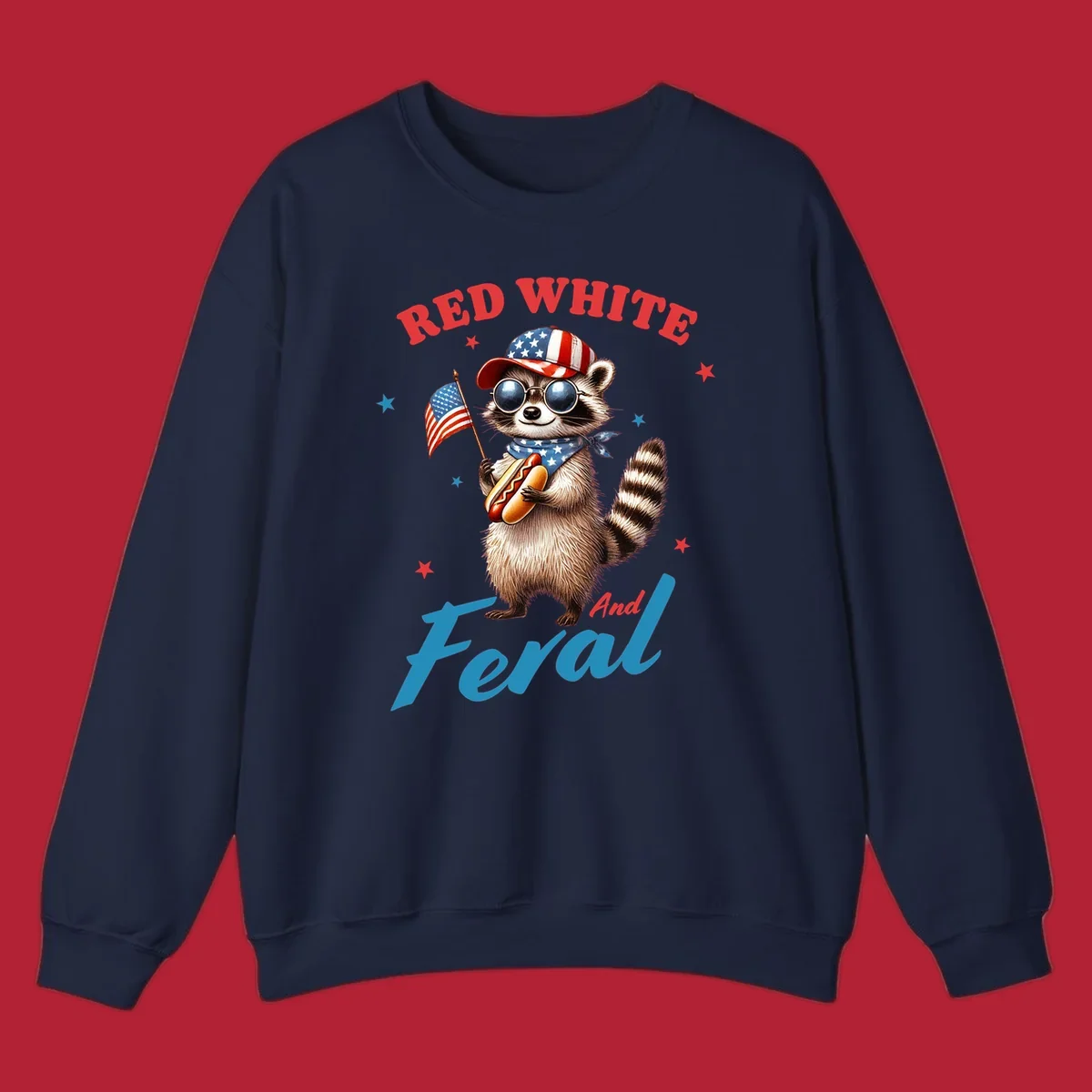 A cartoon raccoon wearing a patriotic hat and bandana, holding an American flag and a hot dog, with 'Red White And Feral' text. This is a red-white-feral-raccoon design.
