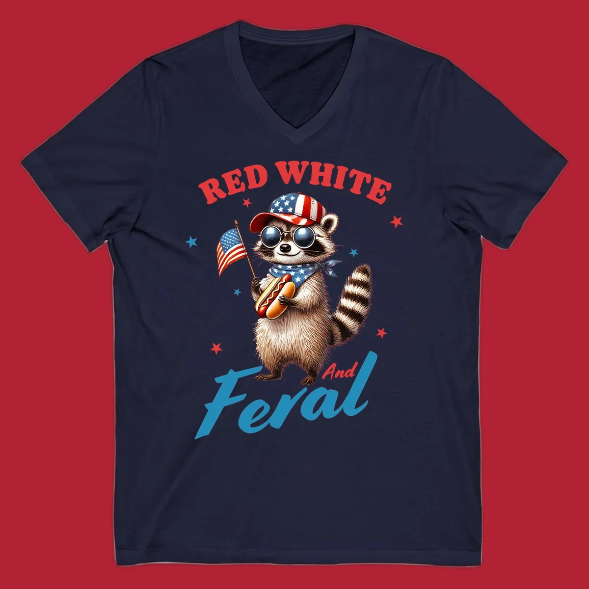 A cartoon raccoon wearing a patriotic hat and bandana, holding an American flag and a hot dog, with 'Red White And Feral' text. This is a red-white-feral-raccoon design.