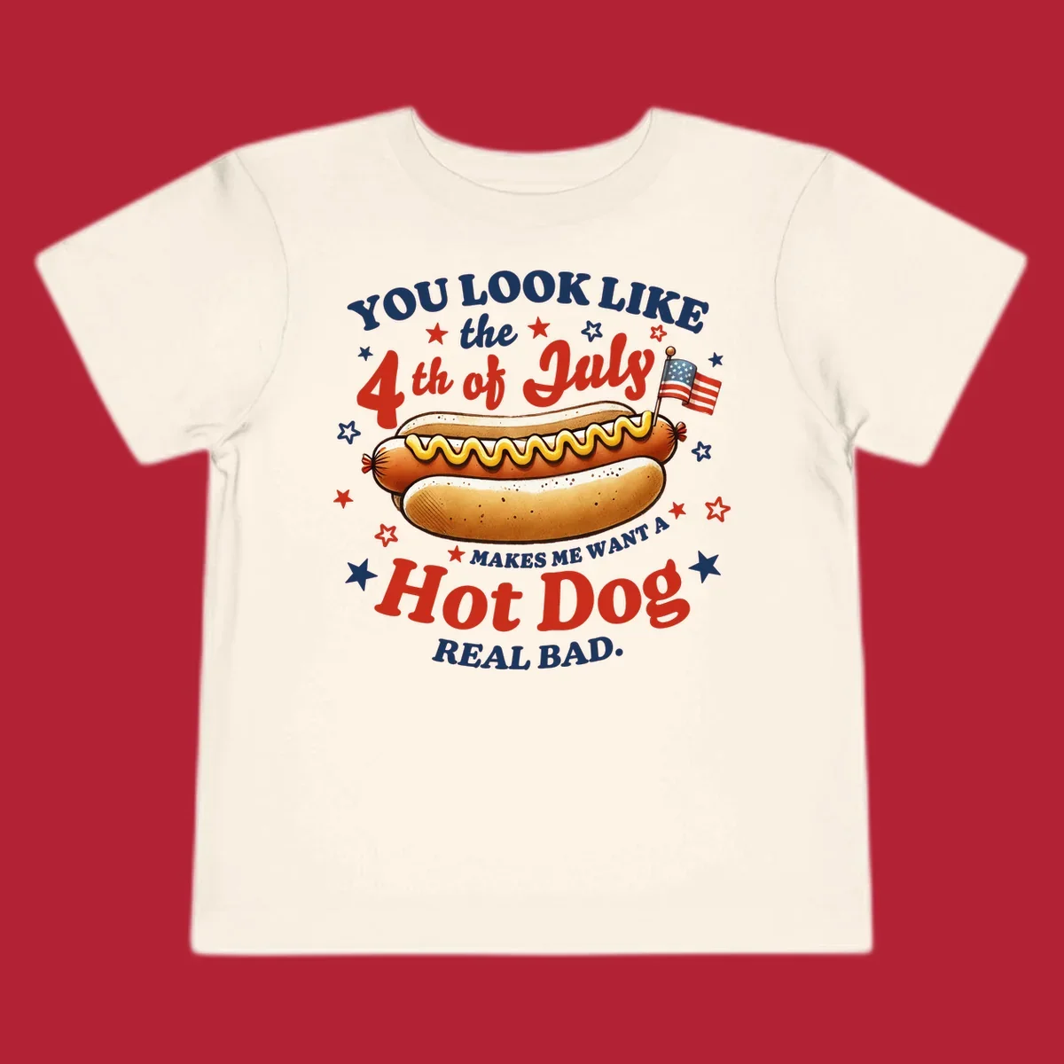 An illustrated hot dog with mustard, American flags, and stars. Text reads "YOU LOOK LIKE the 4th of July MAKES ME WANT A Hot Dog REAL BAD." you-look-like-4th-july design.
