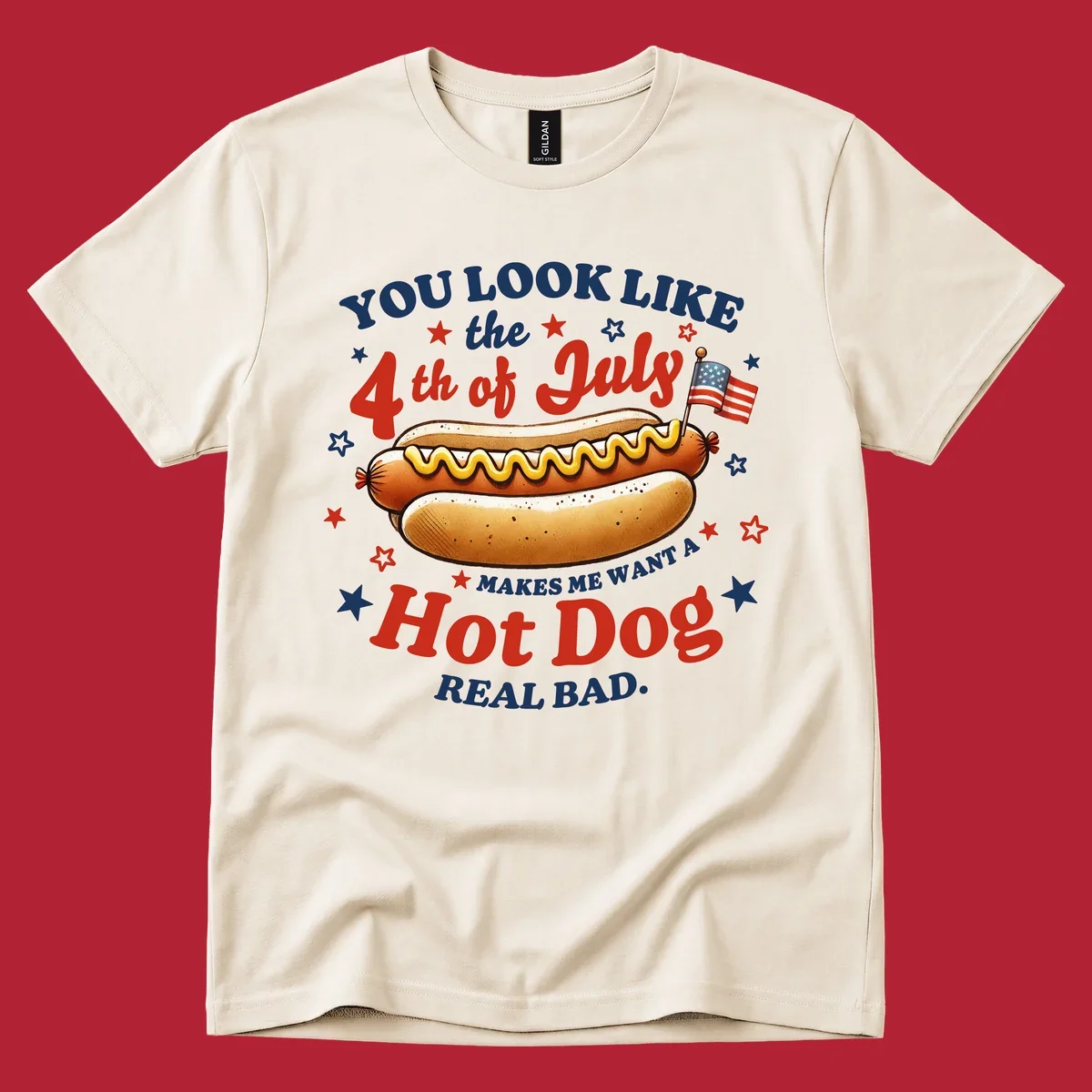 An illustrated hot dog with mustard, American flags, and stars. Text reads "YOU LOOK LIKE the 4th of July MAKES ME WANT A Hot Dog REAL BAD." you-look-like-4th-july design.