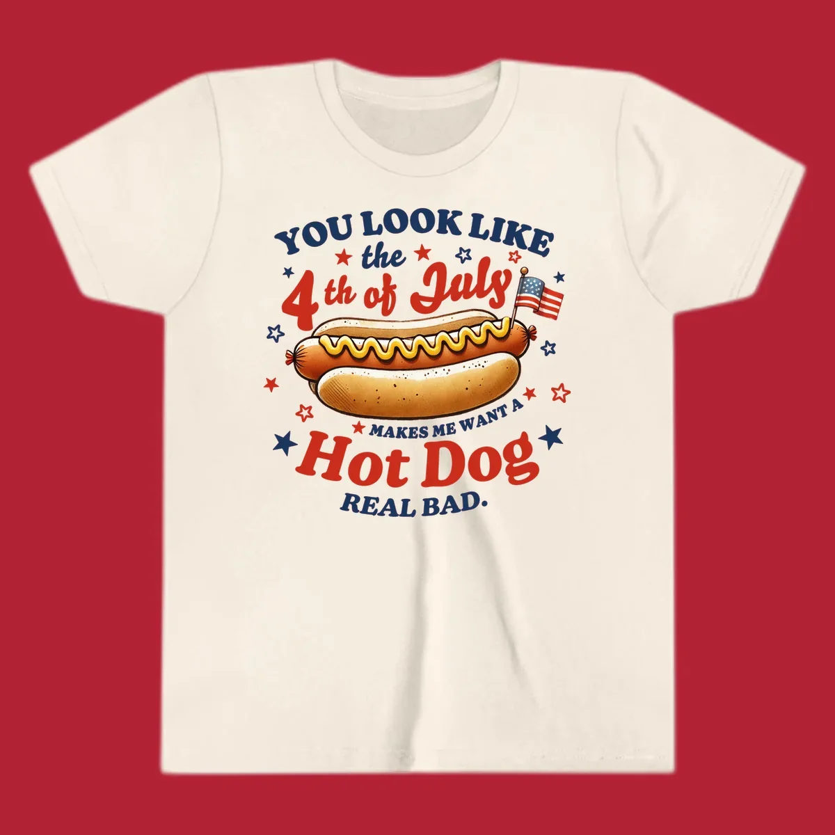 An illustrated hot dog with mustard, American flags, and stars. Text reads "YOU LOOK LIKE the 4th of July MAKES ME WANT A Hot Dog REAL BAD." you-look-like-4th-july design.