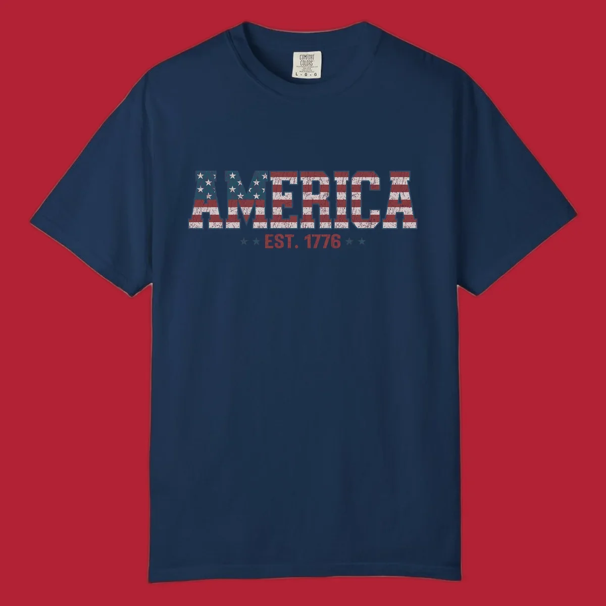 Distressed America Est. 1776 flag design with red, white, and blue flag pattern on block letters and stars.