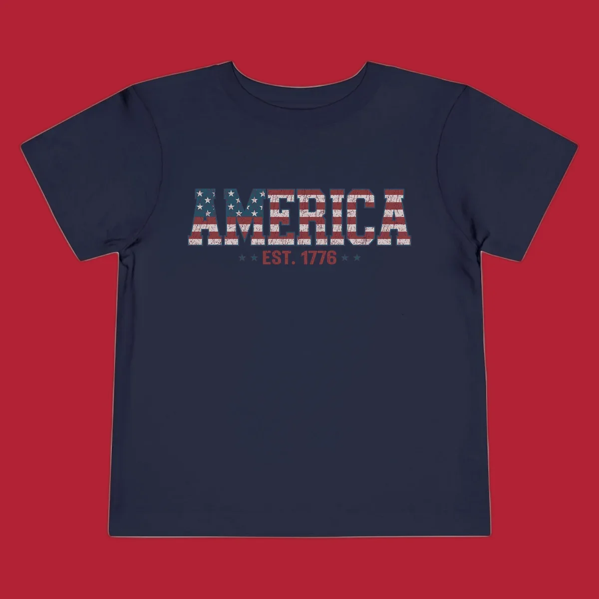Distressed America Est. 1776 flag design with red, white, and blue flag pattern on block letters and stars.