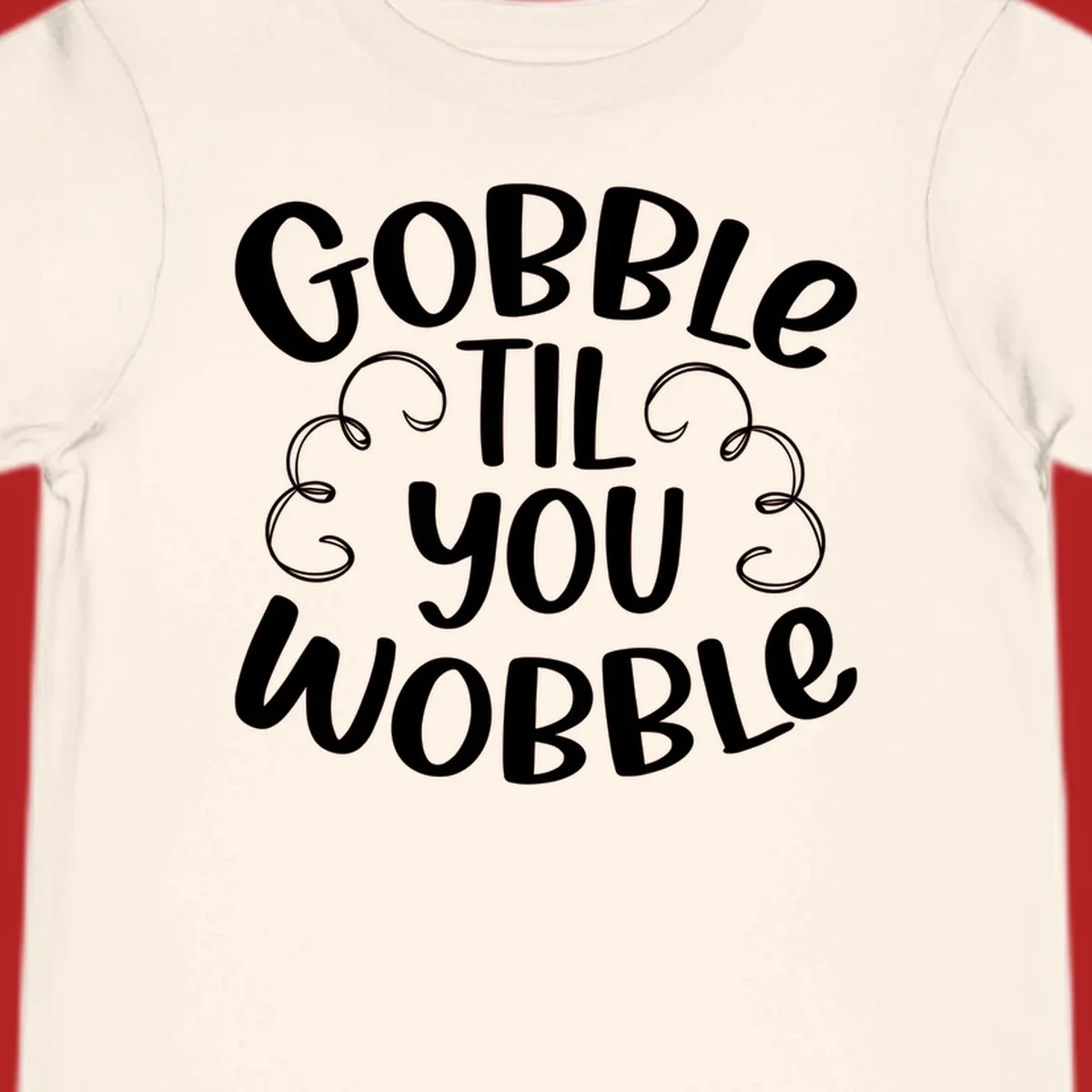 Gobble Til You Wobble Thanksgiving phrase in white text with decorative swirls.