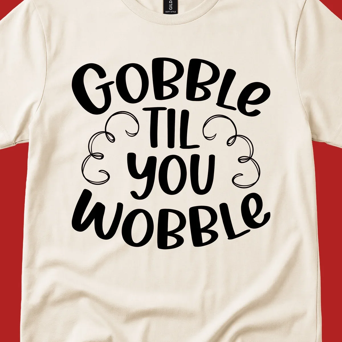Gobble Til You Wobble Thanksgiving phrase in white text with decorative swirls.