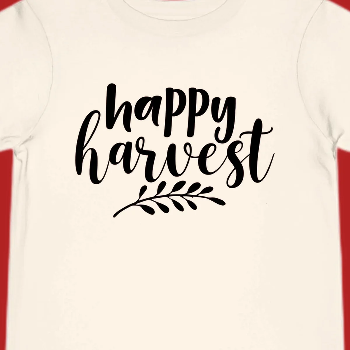 Happy harvest script text with a leaf sprig, suitable for fall and Thanksgiving.