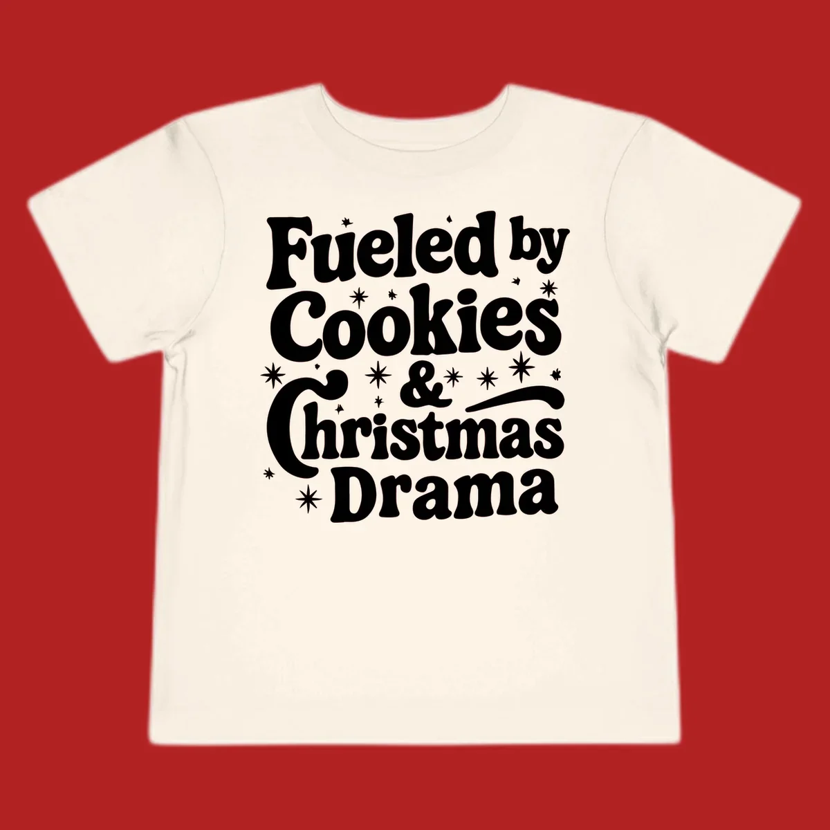 Text design 'Fueled by Cookies & Christmas Drama' with stars, for Christmas.