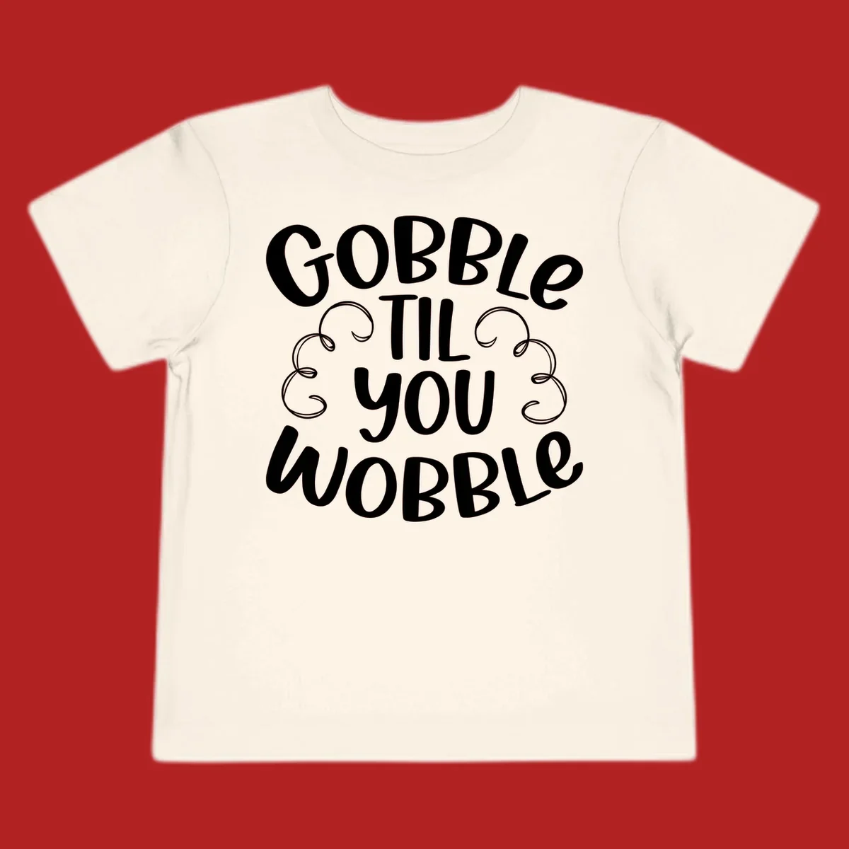 Gobble Til You Wobble Thanksgiving phrase in white text with decorative swirls.