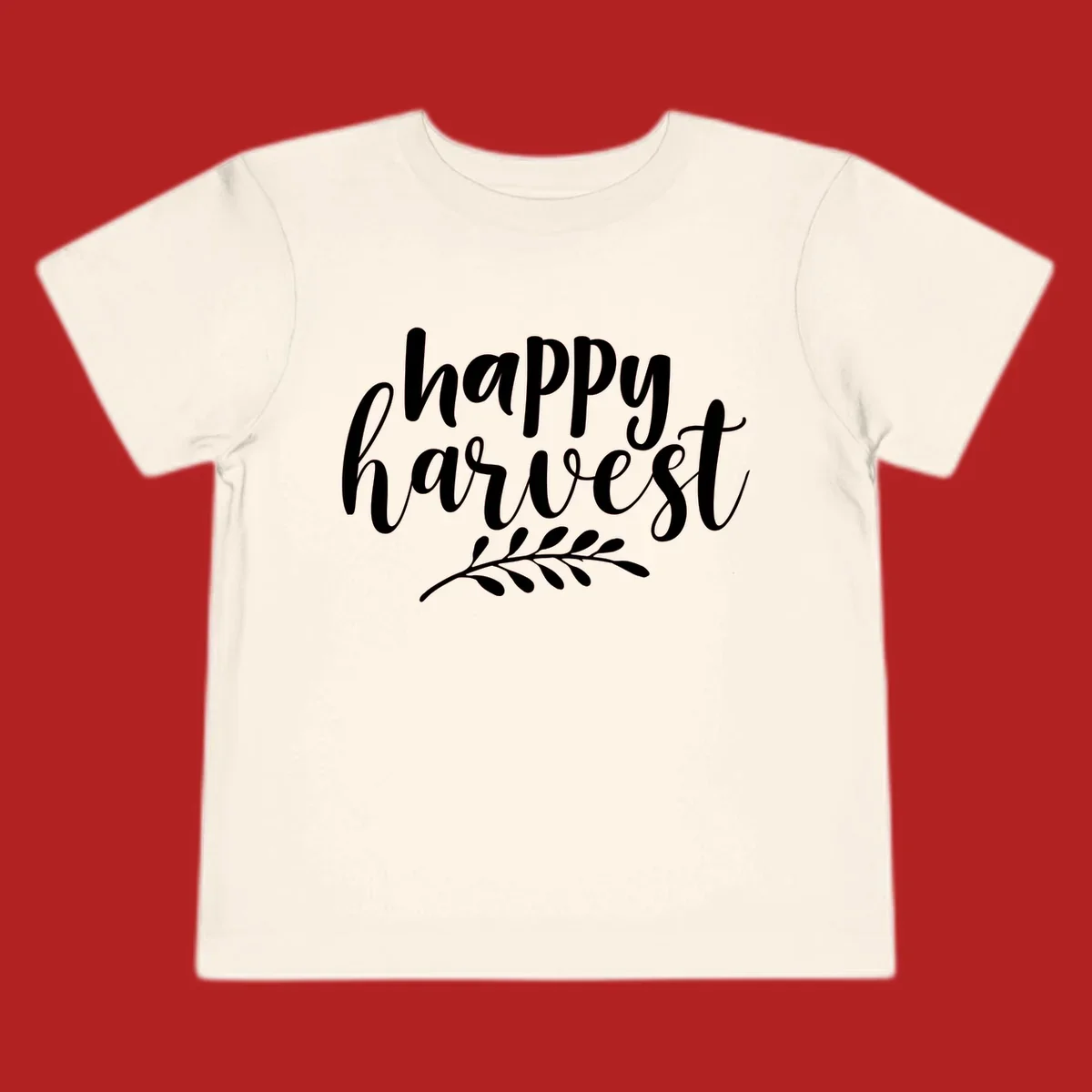 Happy harvest script text with a leaf sprig, suitable for fall and Thanksgiving.