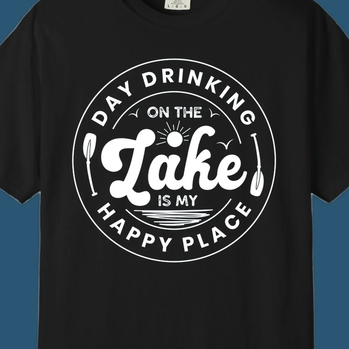 Circular badge design with text 'Day Drinking On The Lake Is My Happy Place' and lake-themed graphics.