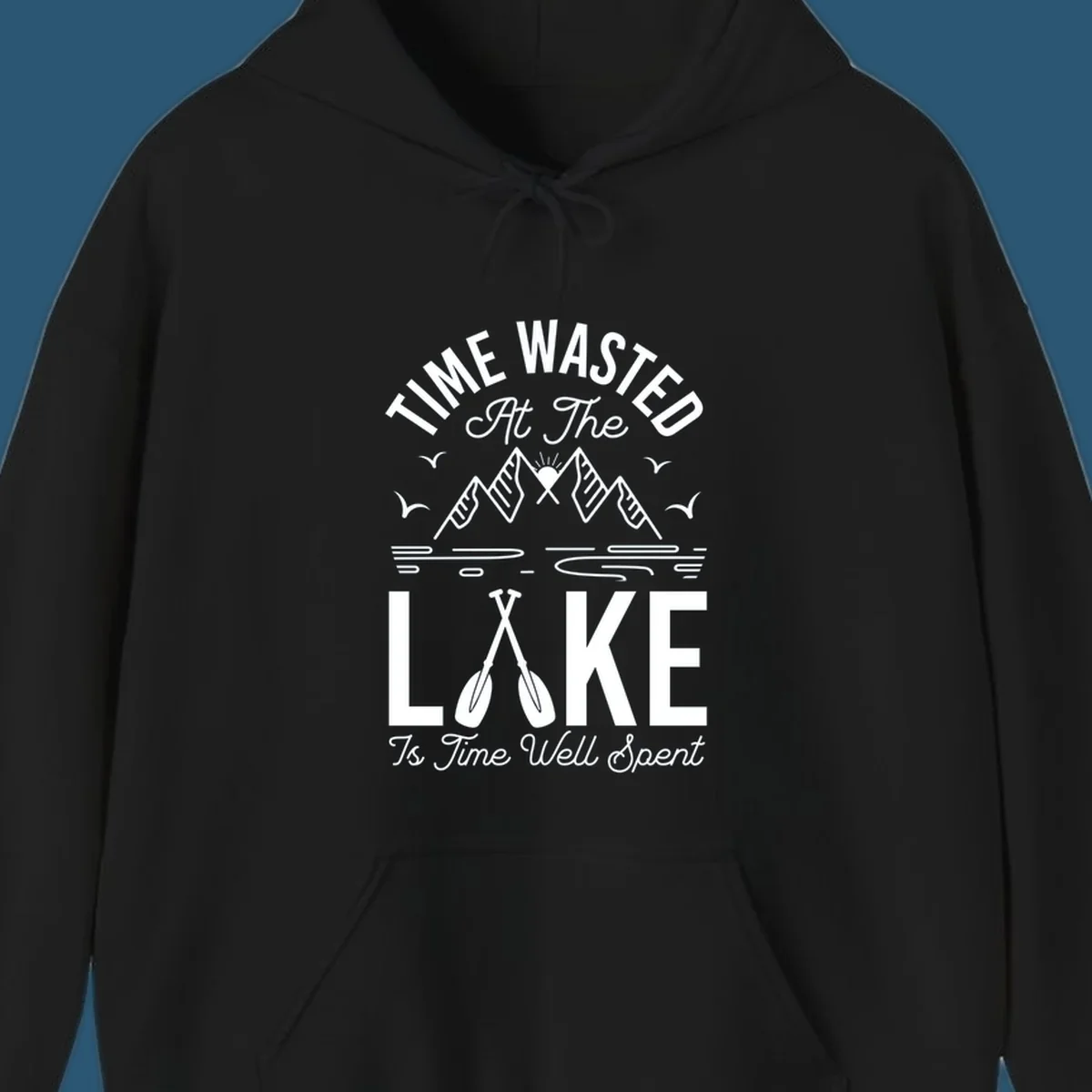 Illustration of mountains, sun, birds, and oars with text 'Time Wasted At The Lake Is Time Well Spent'.