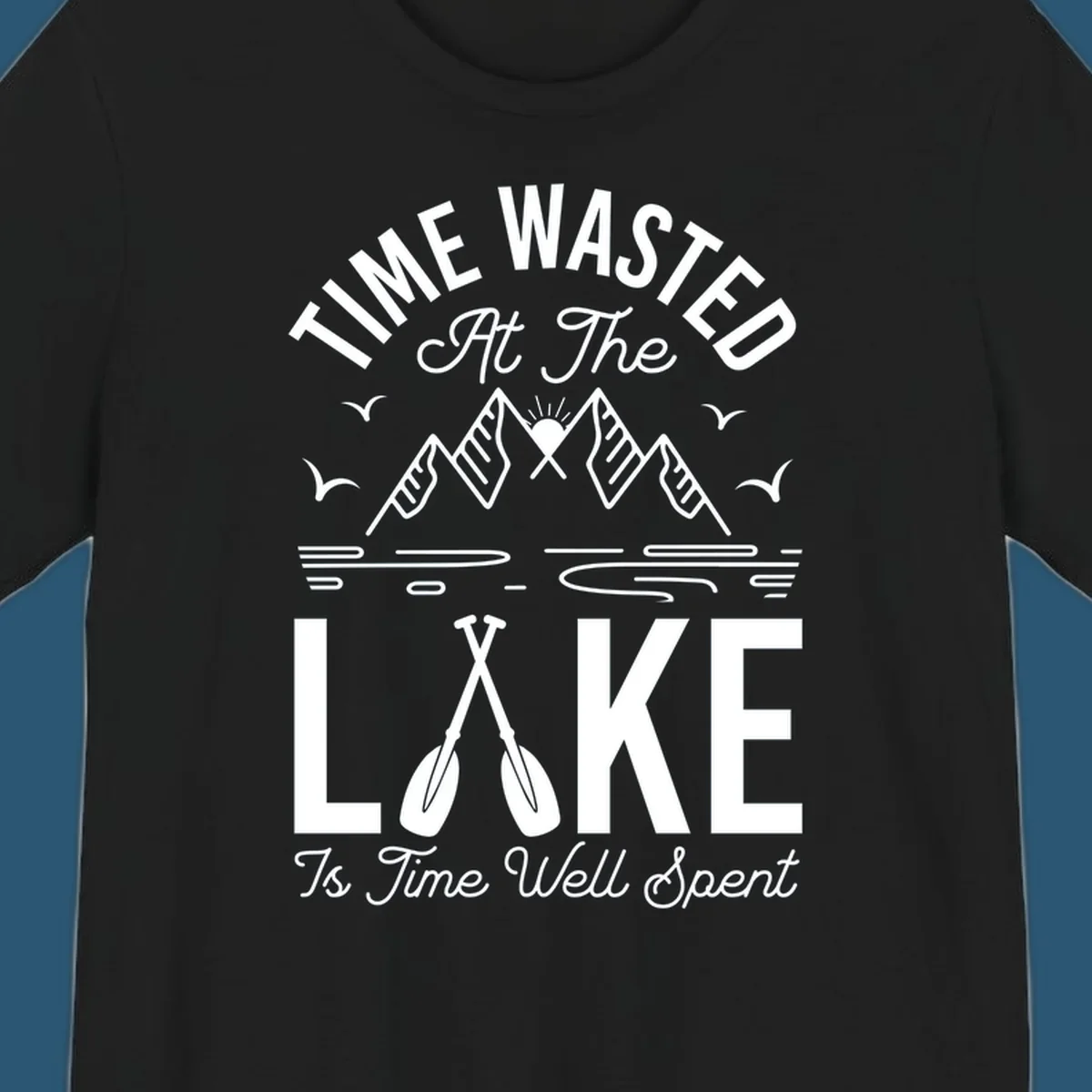 Illustration of mountains, sun, birds, and oars with text 'Time Wasted At The Lake Is Time Well Spent'.
