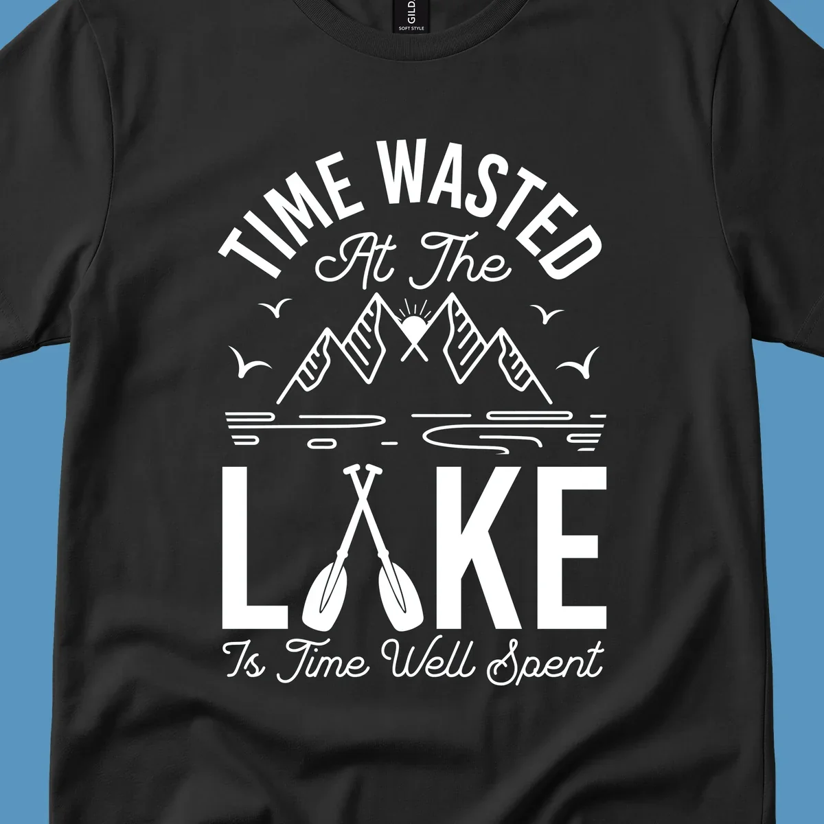 Illustration of mountains, sun, birds, and oars with text 'Time Wasted At The Lake Is Time Well Spent'.