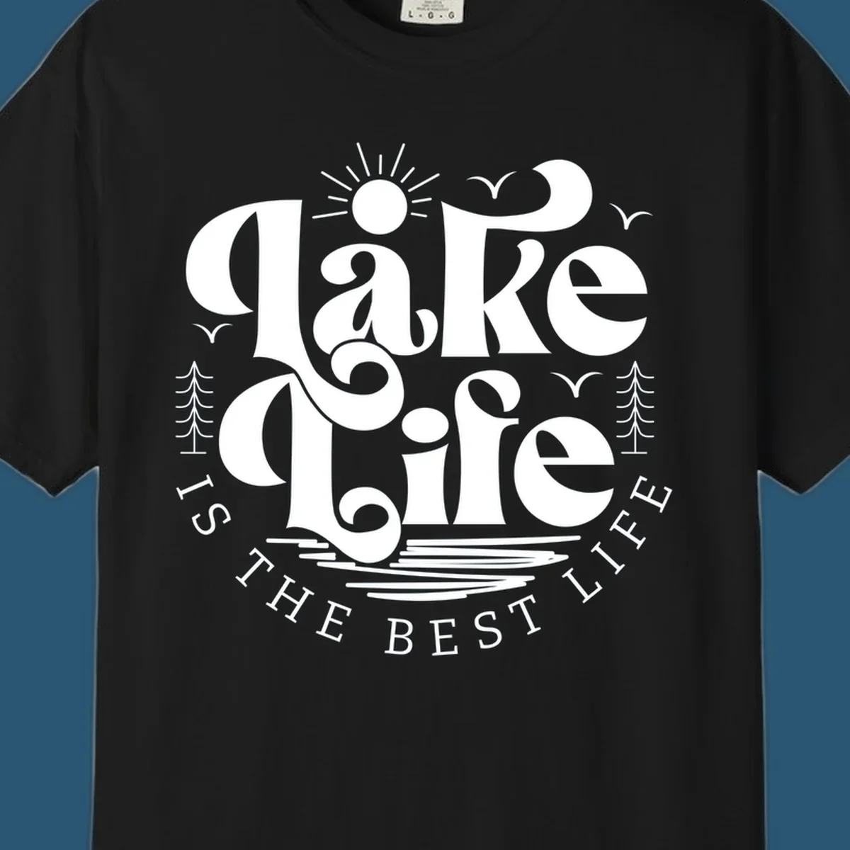Lake life is the best life typography design with sun, birds, trees, and water elements.
