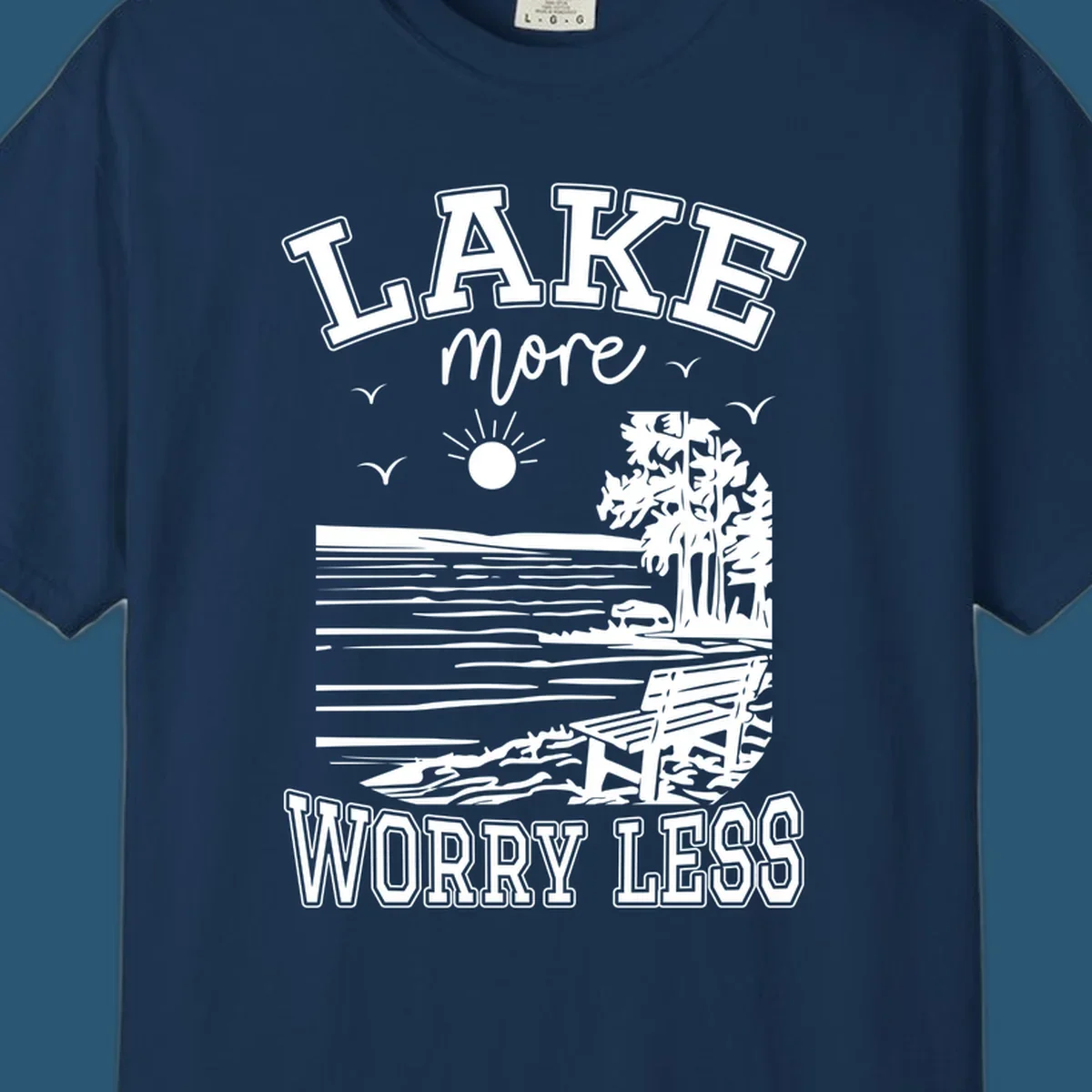 Lake More Worry Less scenic illustration with lake, trees, bench, and sun, white text on black, navy text on white.
