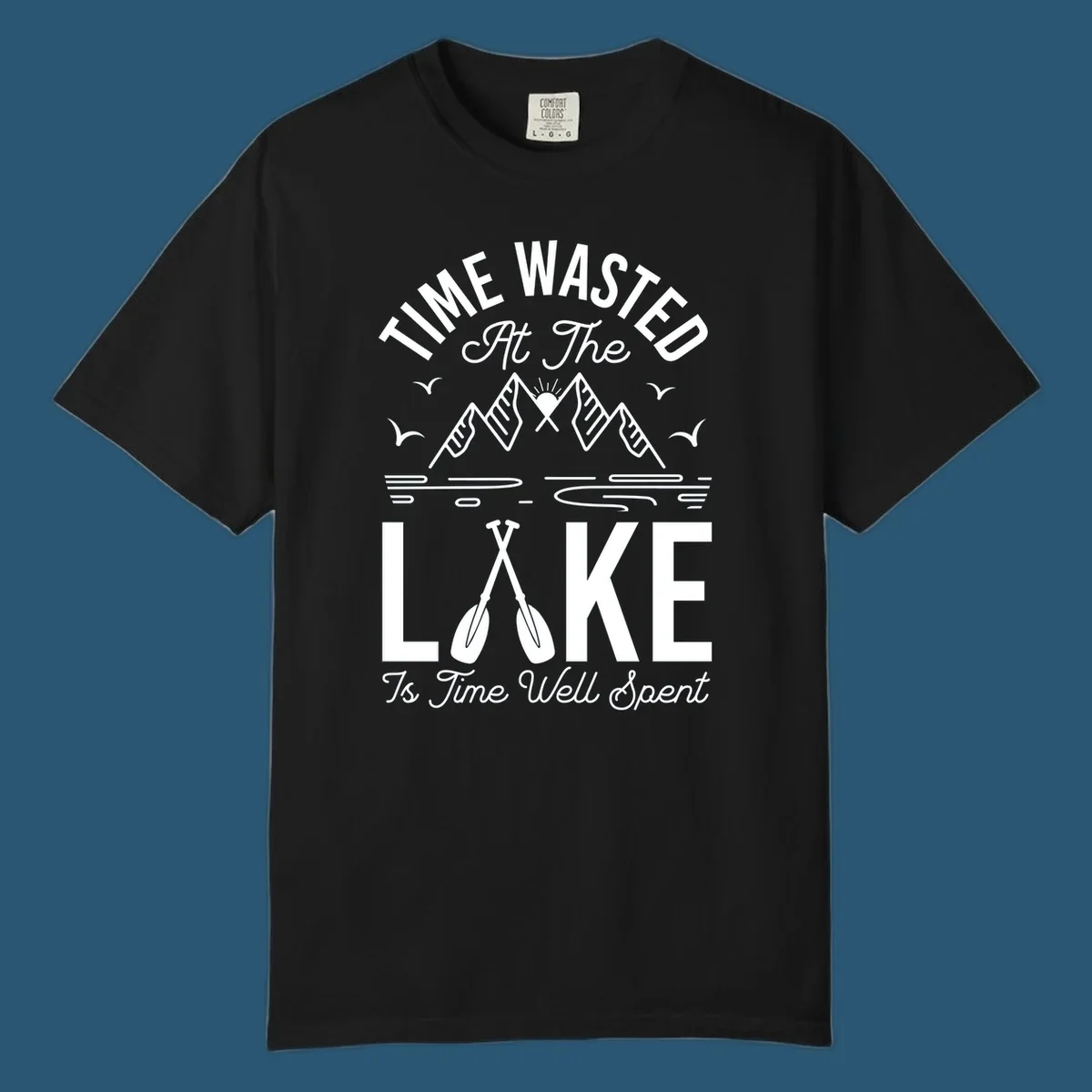 Illustration of mountains, sun, birds, and oars with text 'Time Wasted At The Lake Is Time Well Spent'.