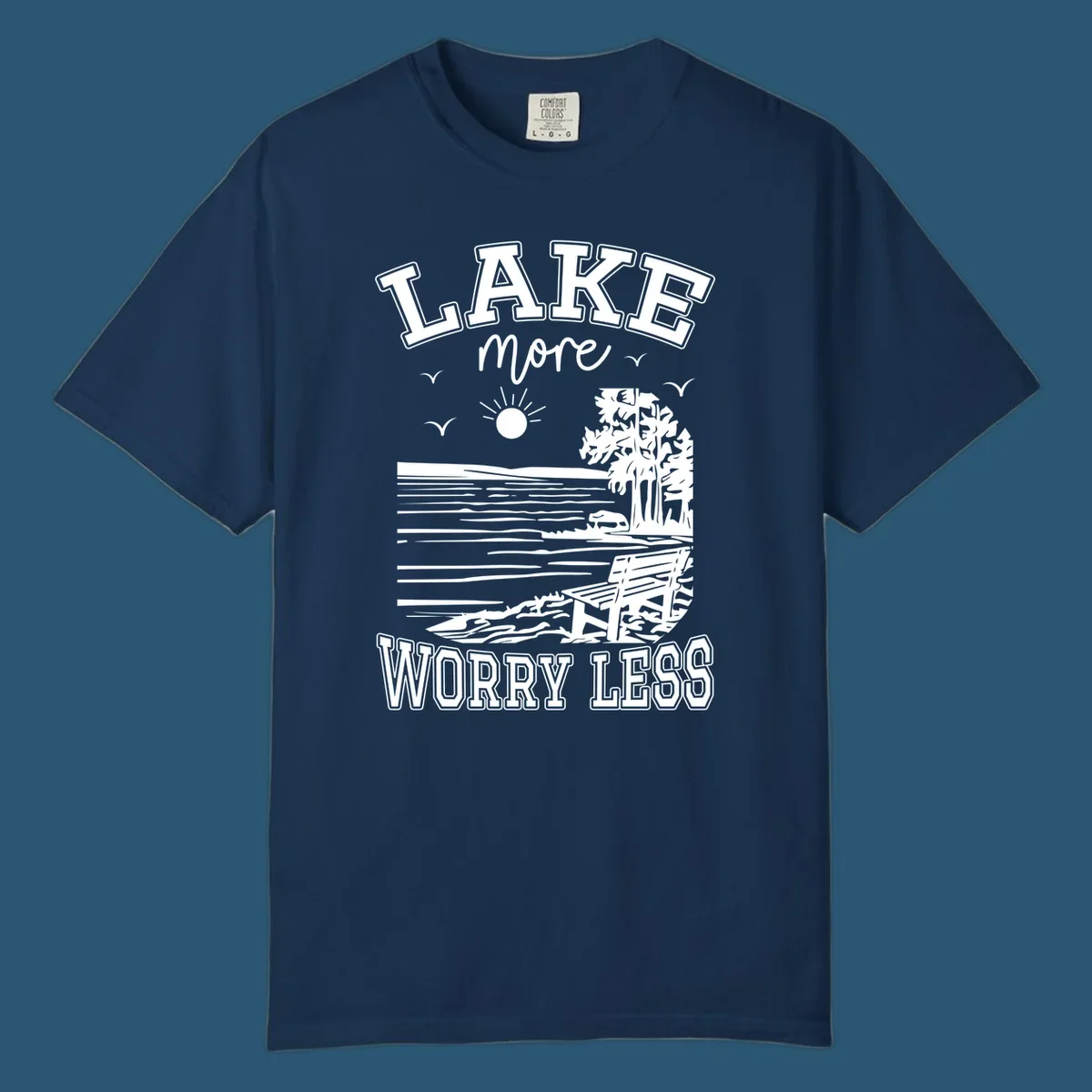 Lake More Worry Less scenic illustration with lake, trees, bench, and sun, white text on black, navy text on white.