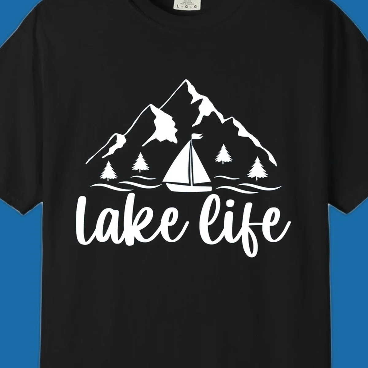 Lake life mountain sailboat scenic design with mountains, trees, sailboat, and text.