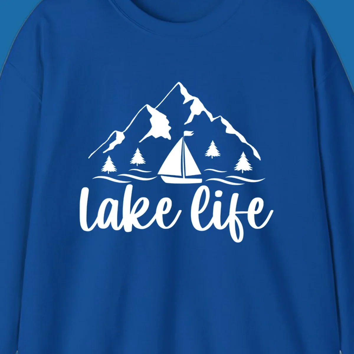 Lake life mountain sailboat scenic design with mountains, trees, sailboat, and text.