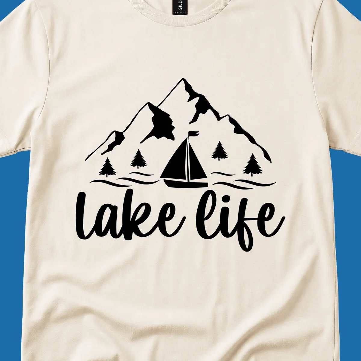 Lake life mountain sailboat scenic design with mountains, trees, sailboat, and text.