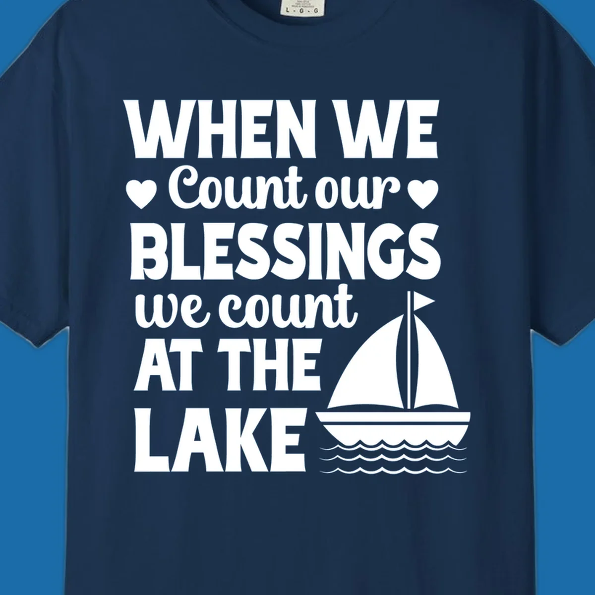 Text reads 'When We Count Our Blessings We Count At The Lake' with a sailboat graphic, lake-life-blessings design.