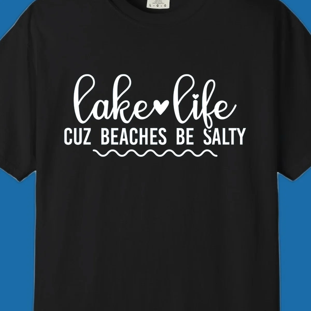 Lake life cuz beaches be salty text design with heart and wavy lines.