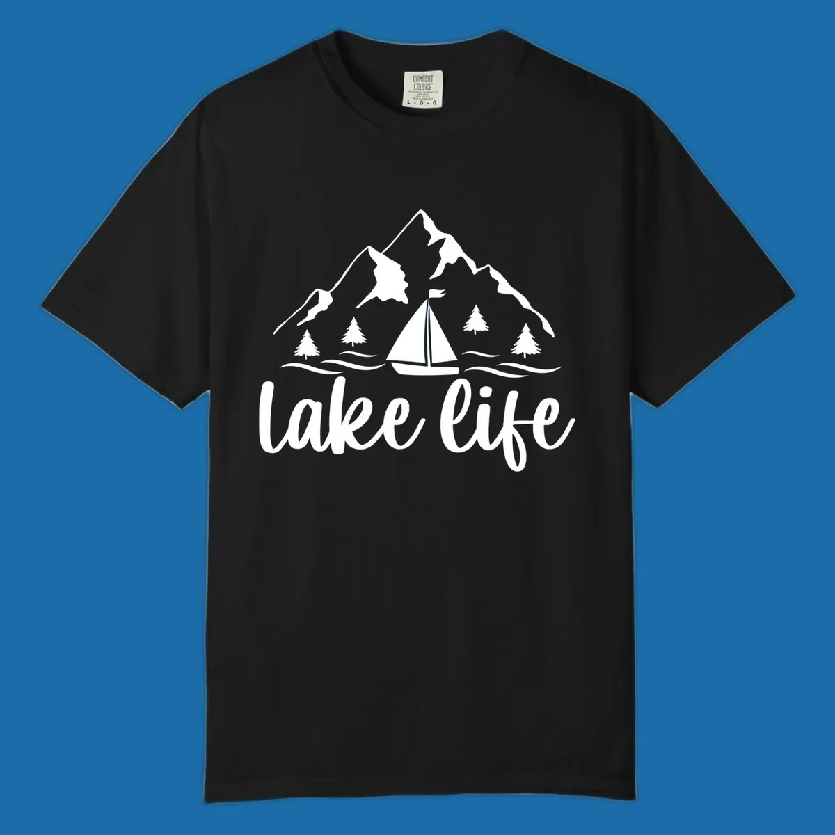 Lake life mountain sailboat scenic design with mountains, trees, sailboat, and text.