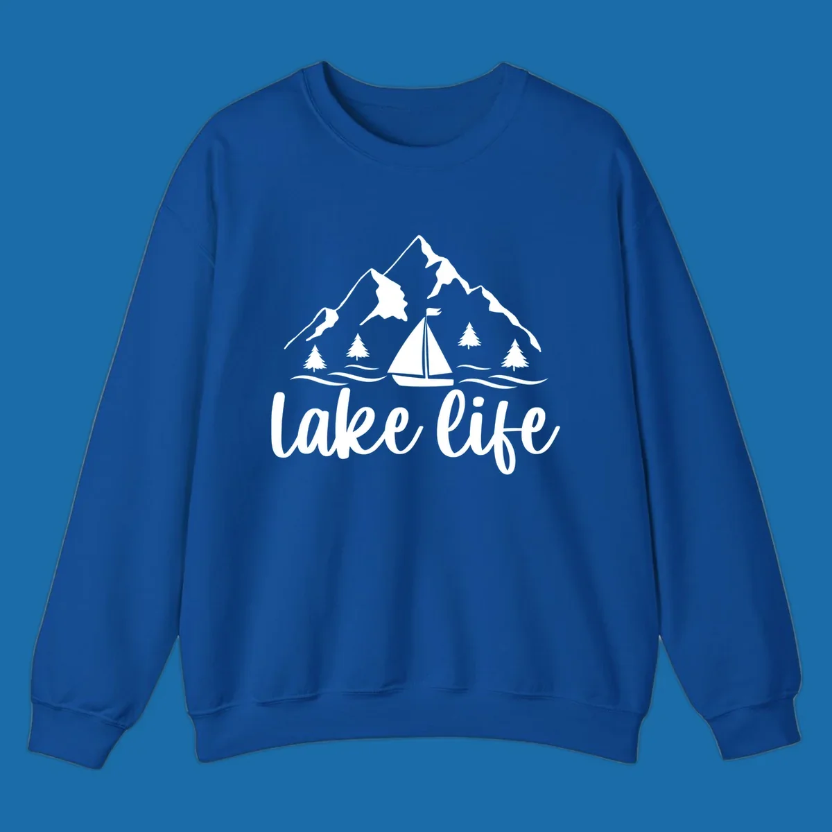 Lake life mountain sailboat scenic design with mountains, trees, sailboat, and text.