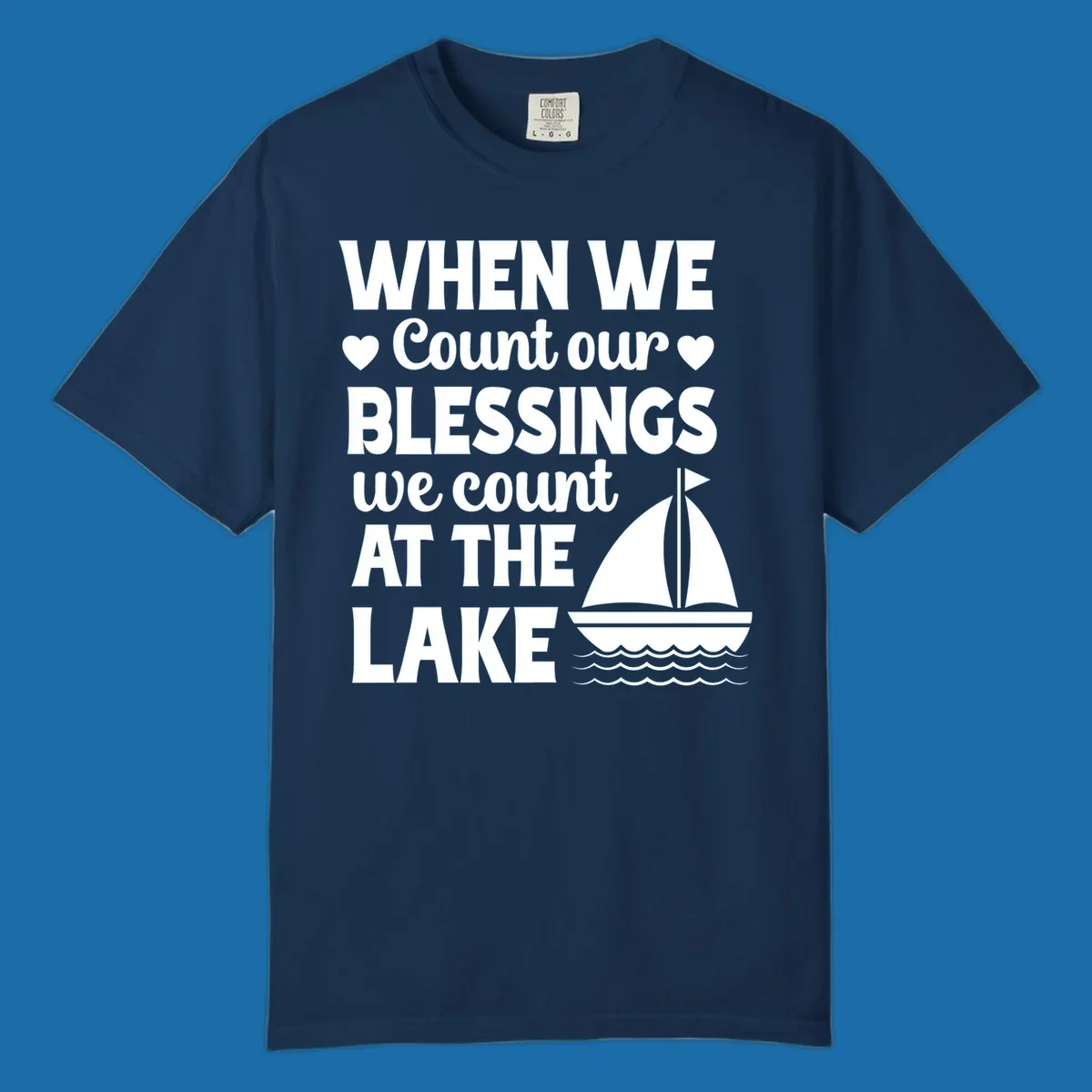 Text reads 'When We Count Our Blessings We Count At The Lake' with a sailboat graphic, lake-life-blessings design.