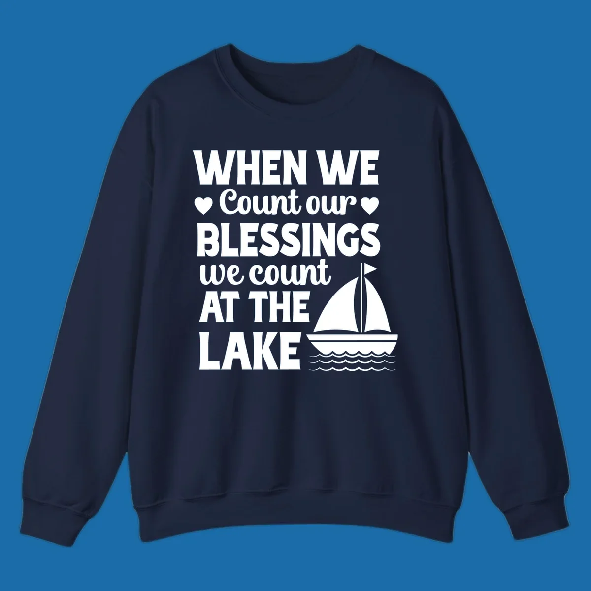 Text reads 'When We Count Our Blessings We Count At The Lake' with a sailboat graphic, lake-life-blessings design.