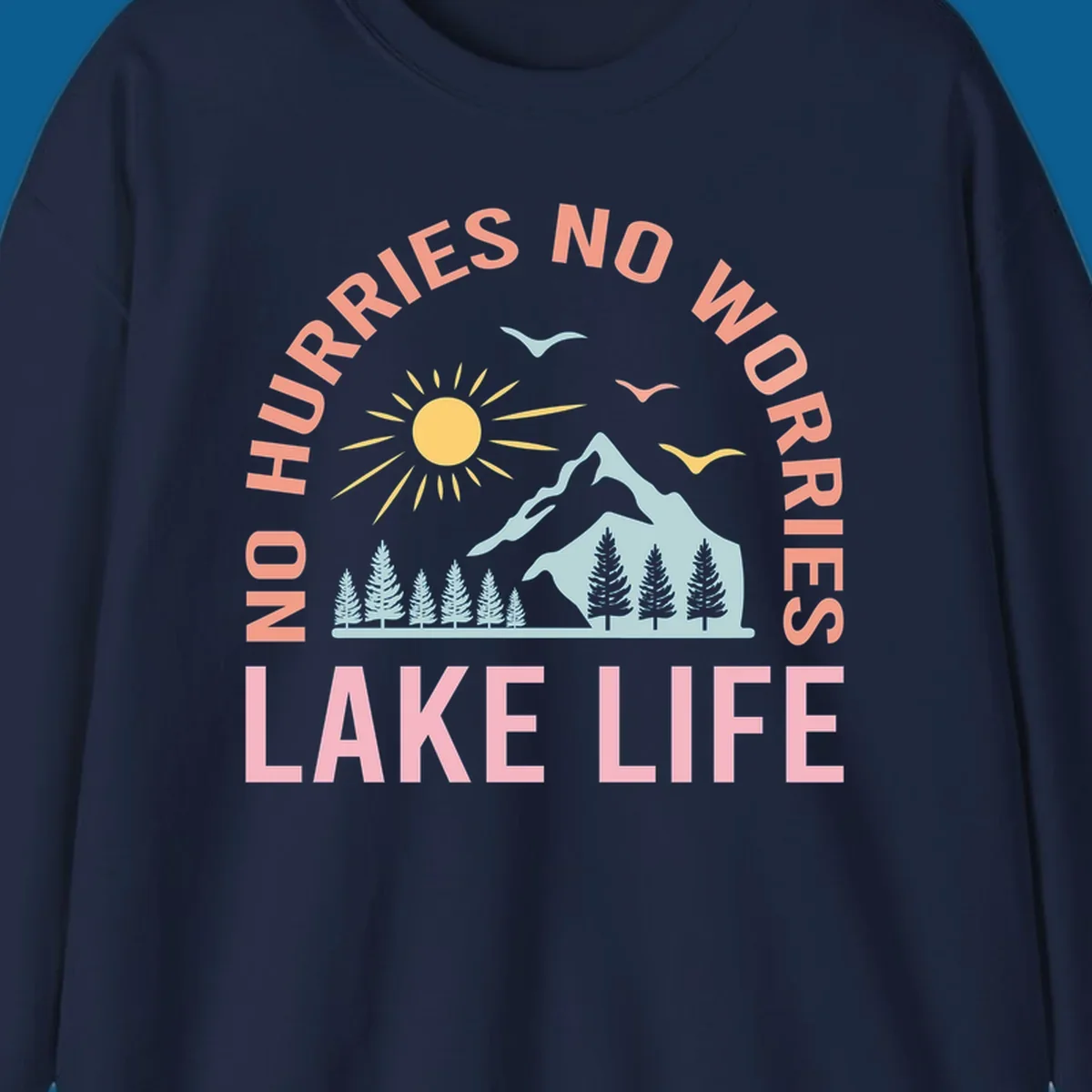 Lake life scenic design with mountains, sun, trees, and no worries text.