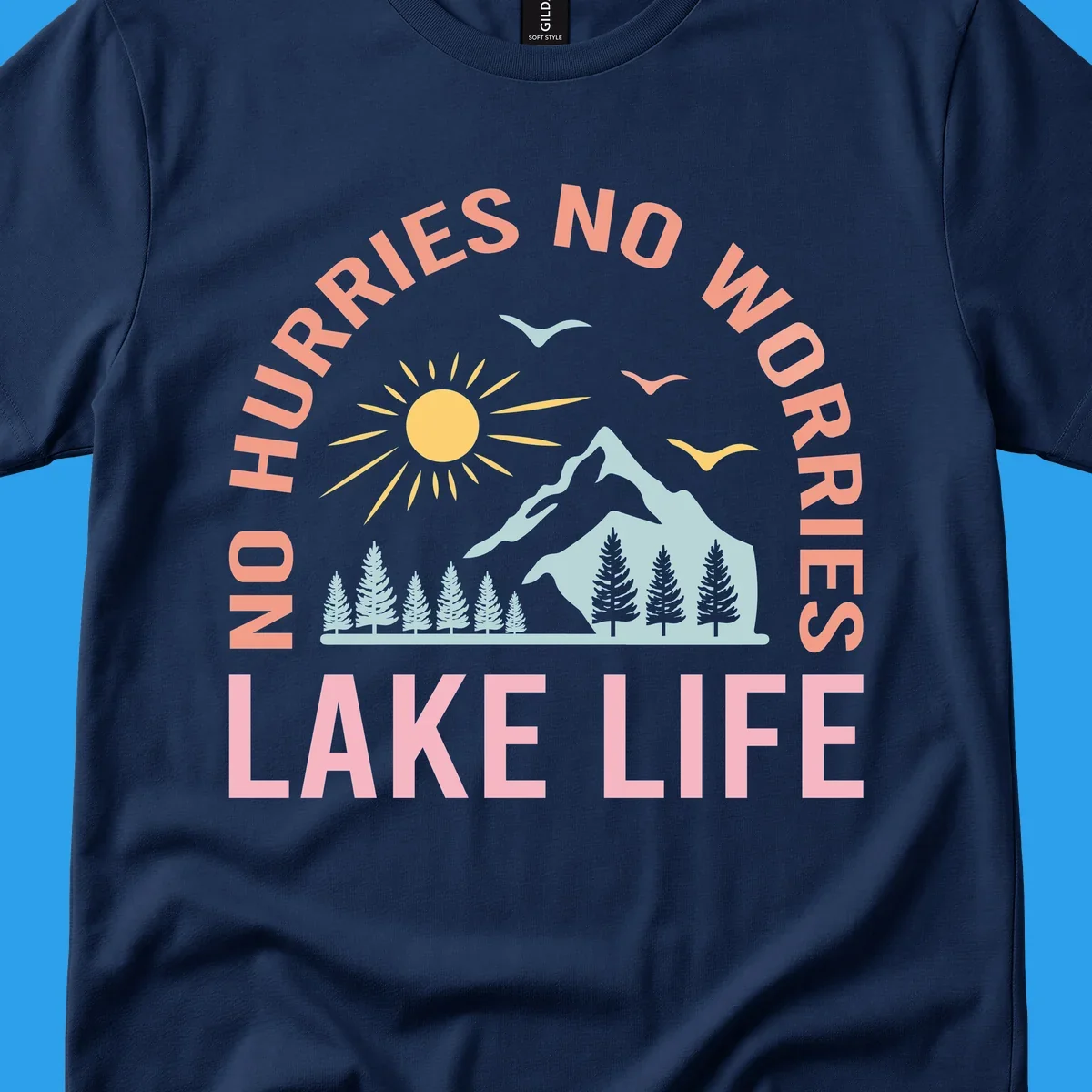 Lake life scenic design with mountains, sun, trees, and no worries text.
