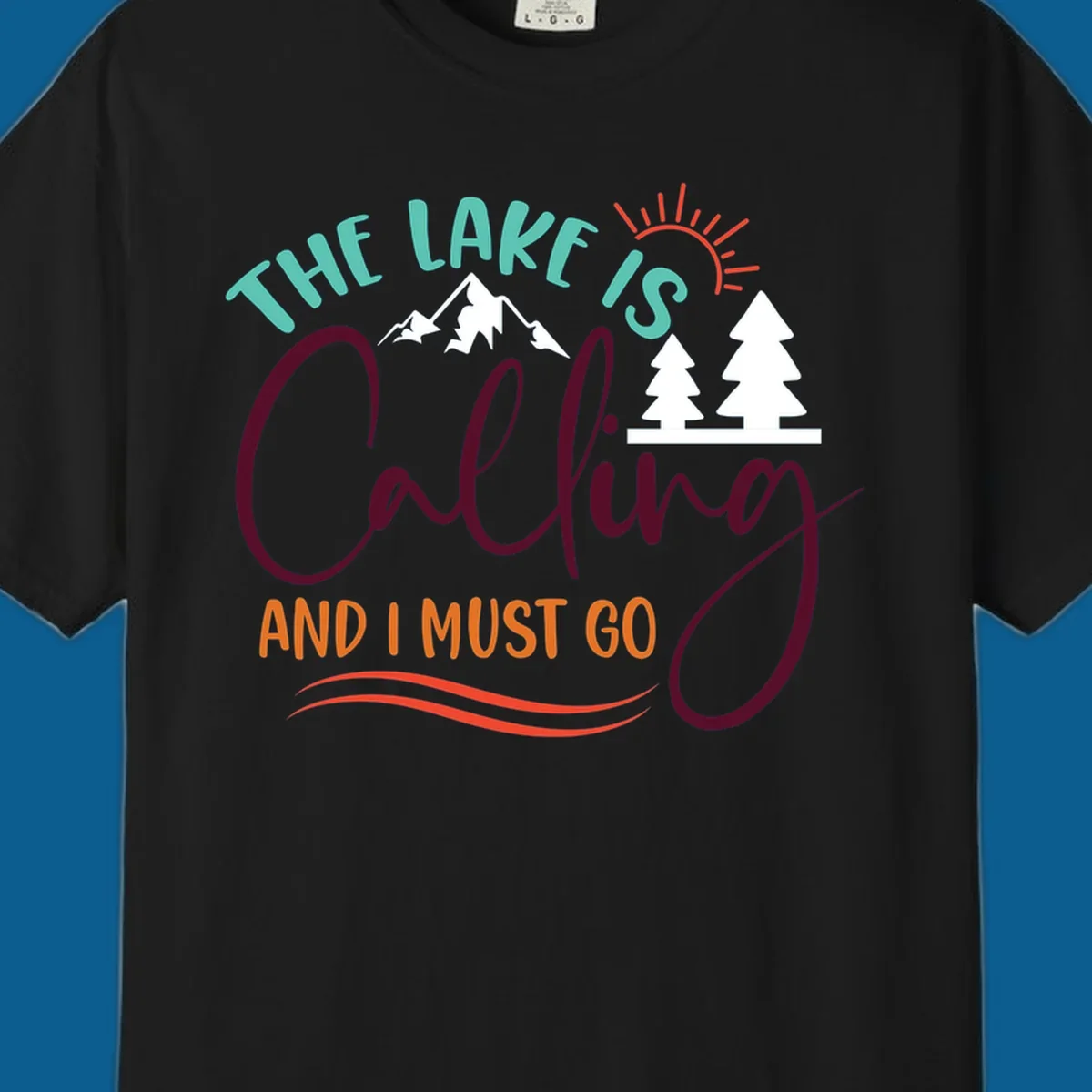 The Lake Is Calling And I Must Go nature graphic with mountains, trees, and sun rays.