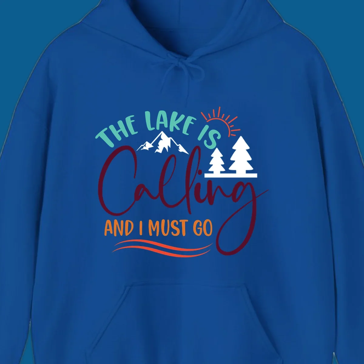 The Lake Is Calling And I Must Go nature graphic with mountains, trees, and sun rays.