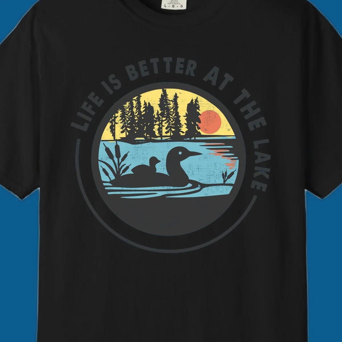 Circular lake scene with loons and trees, text "Life Is Better At The Lake".