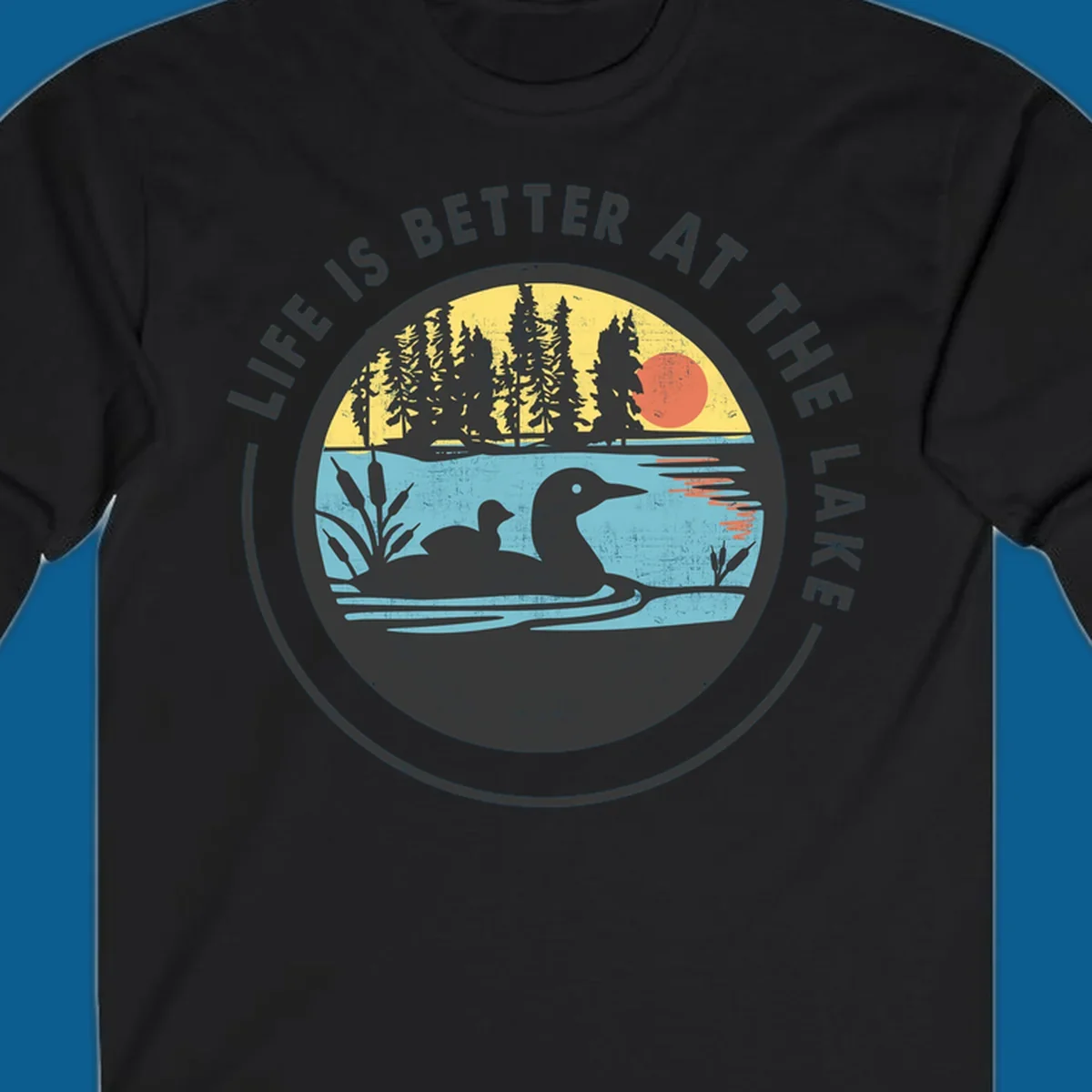 Circular lake scene with loons and trees, text "Life Is Better At The Lake".