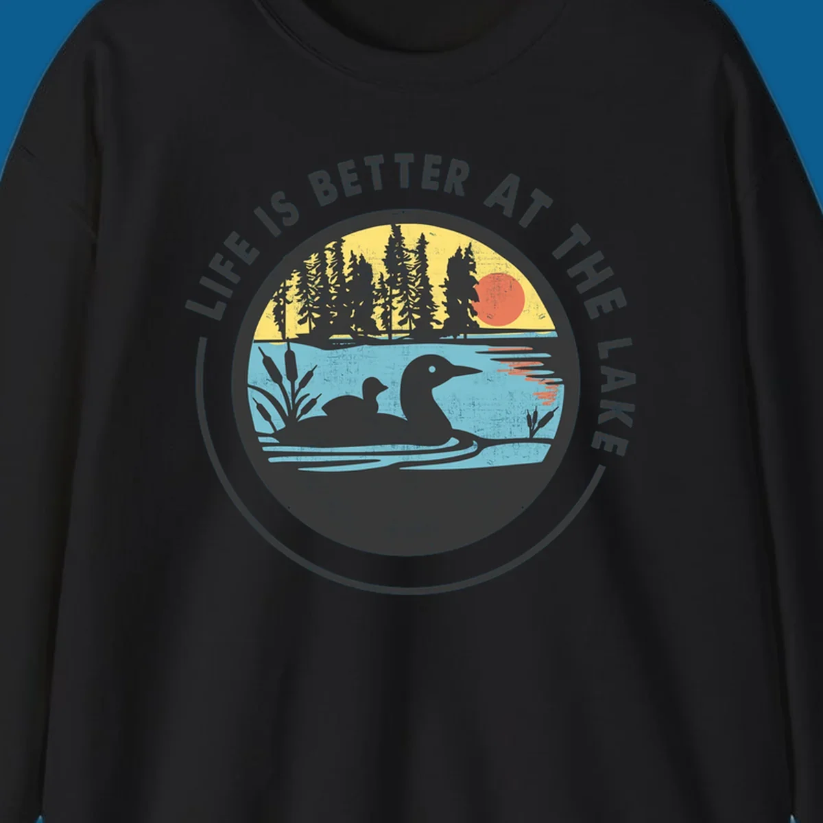 Circular lake scene with loons and trees, text "Life Is Better At The Lake".